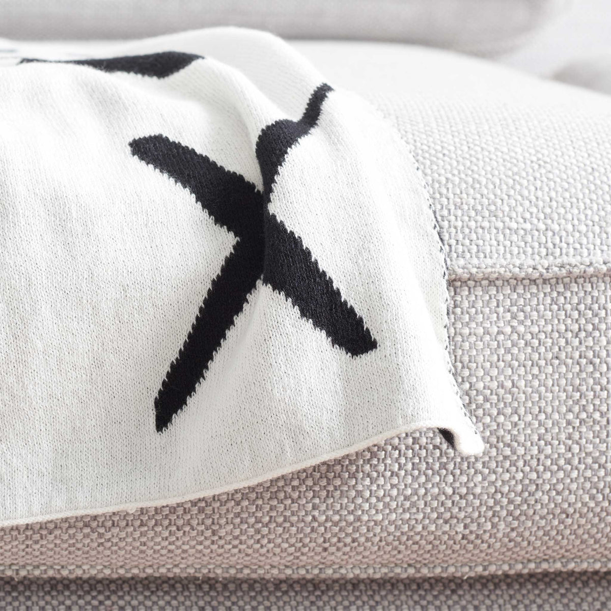 Clean ivory edge with contrasting black X shows the reversible craftsmanship and soft texture || THR404A-5060 || corner_room