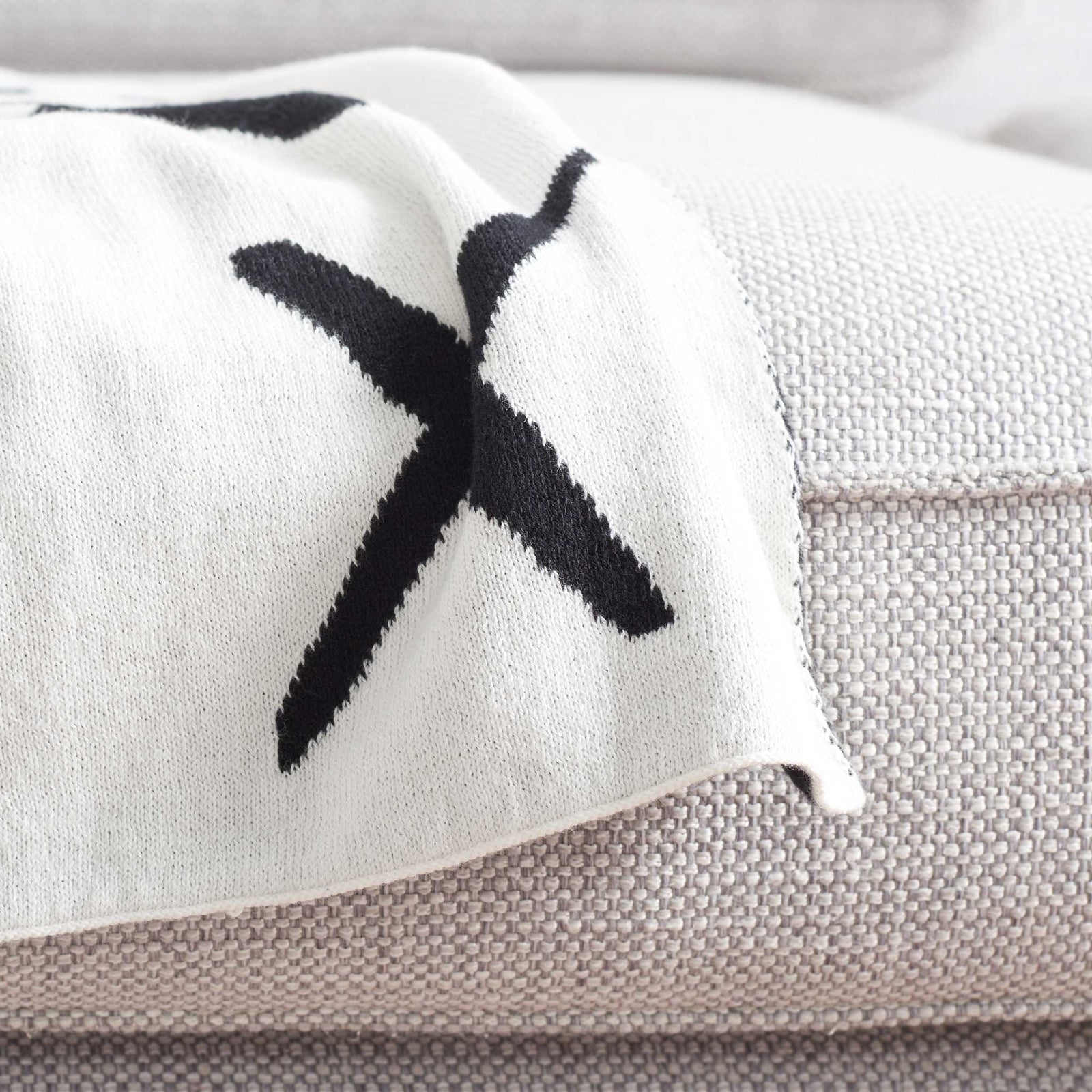 Clean ivory edge with contrasting black X shows the reversible craftsmanship and soft texture || THR404A-5060 || corner_room