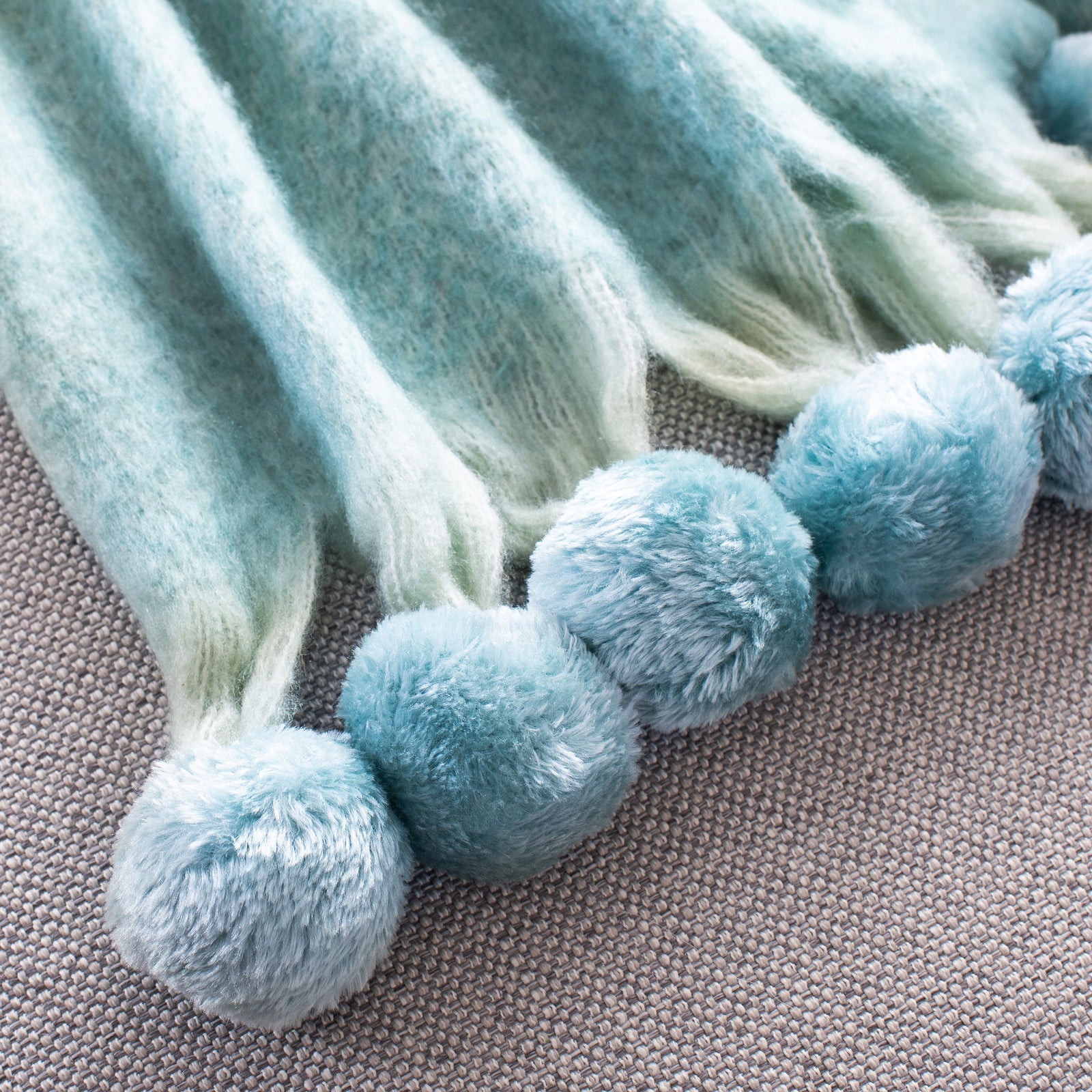 Fluffy blue pom-poms and soft fringe accent the throw's edge || THR619A-5070 || corner_room