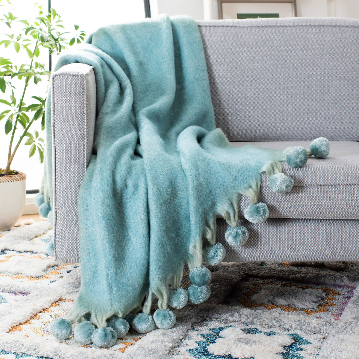 Blue throw adds cozy color to a sofa with cascading pom-poms and fringe || THR619A-5070 || front_angle_room