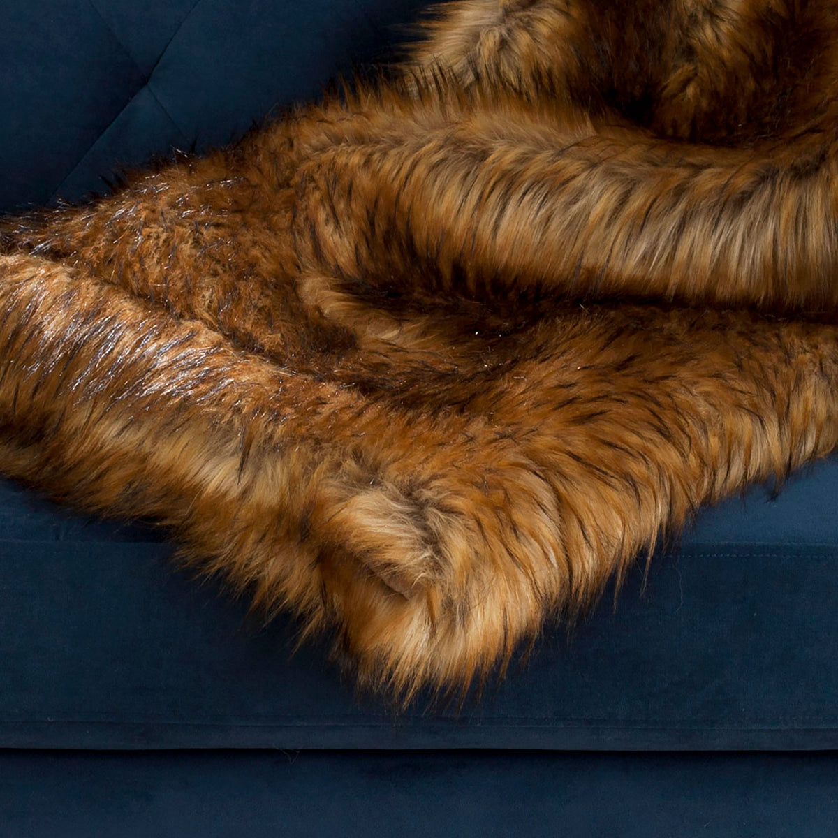 Rich faux fur fibers add cozy texture and warm color while draped across a tufted sofa || THR703A || detail_room