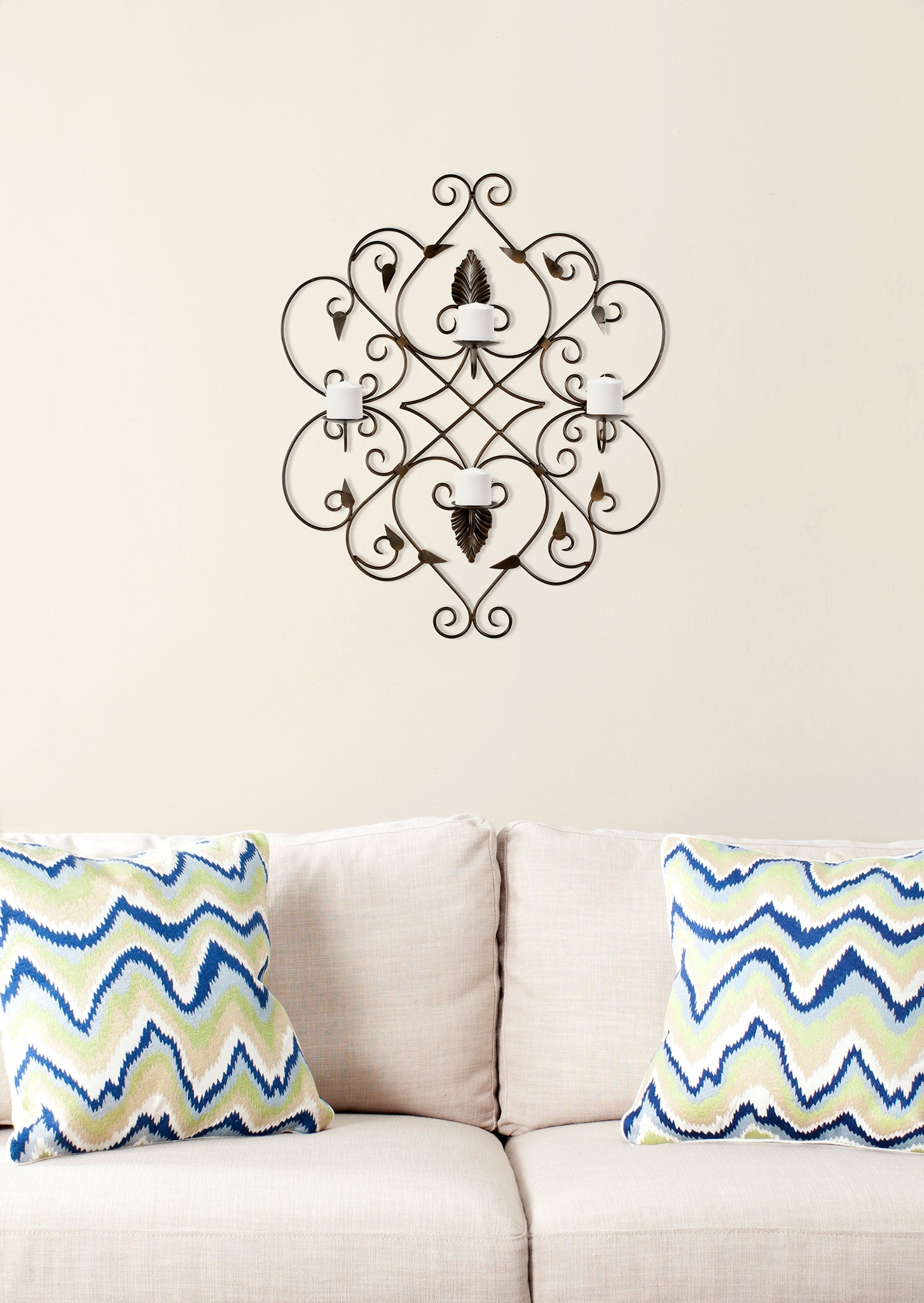 Rust-finished iron scrollwork frames four white pillar candles in a graceful wall accent. || WDC1004A || front_room
