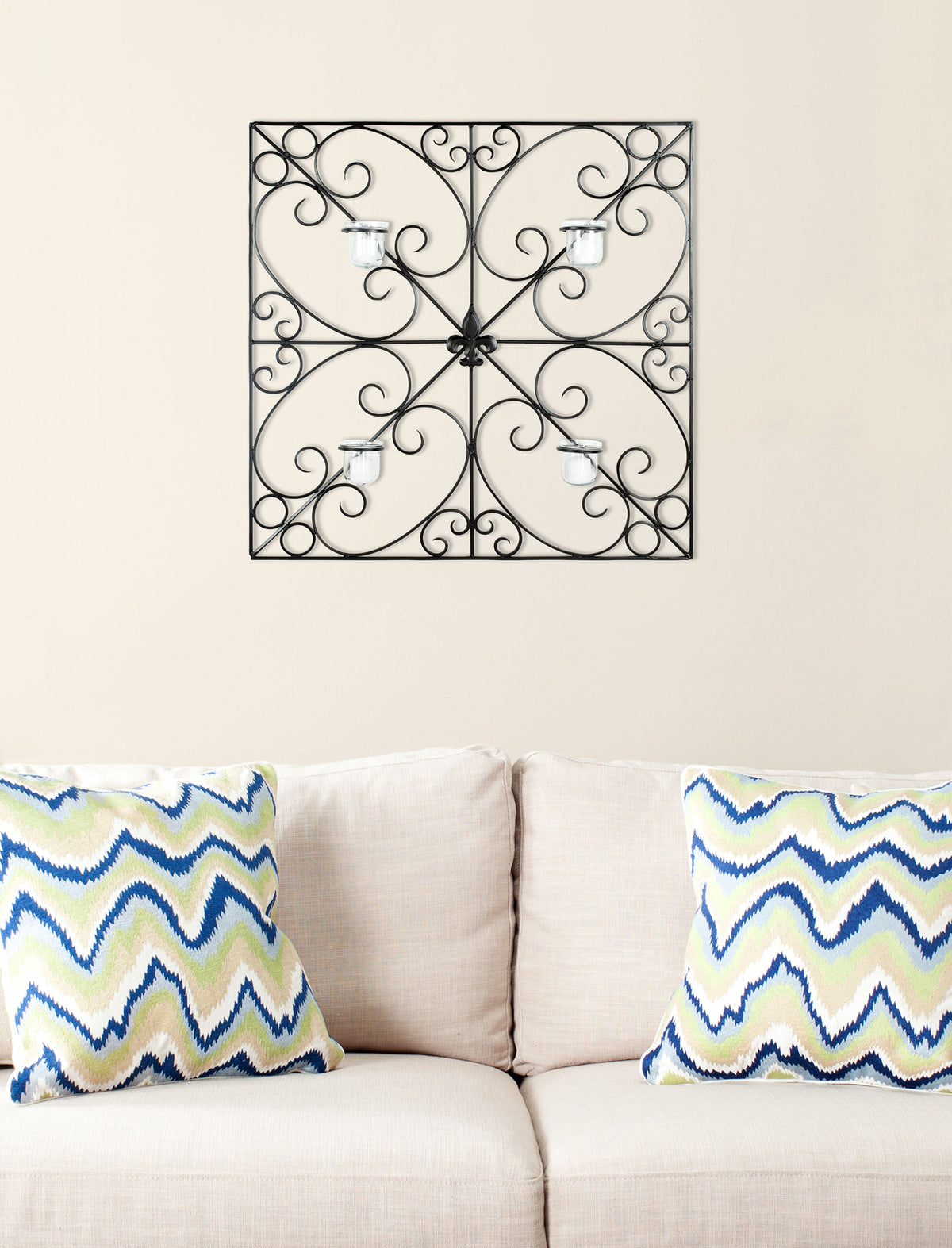 Black iron scrollwork surrounds four glass votives in a symmetrical square wall accent.