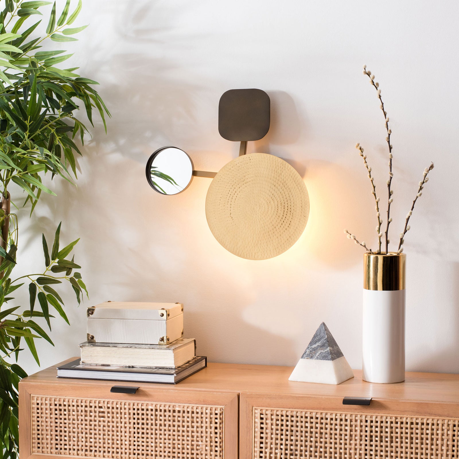 Warm backlighting frames the hammered gold-tone disk and small mirror above a console || WDC1030A || front_on_room