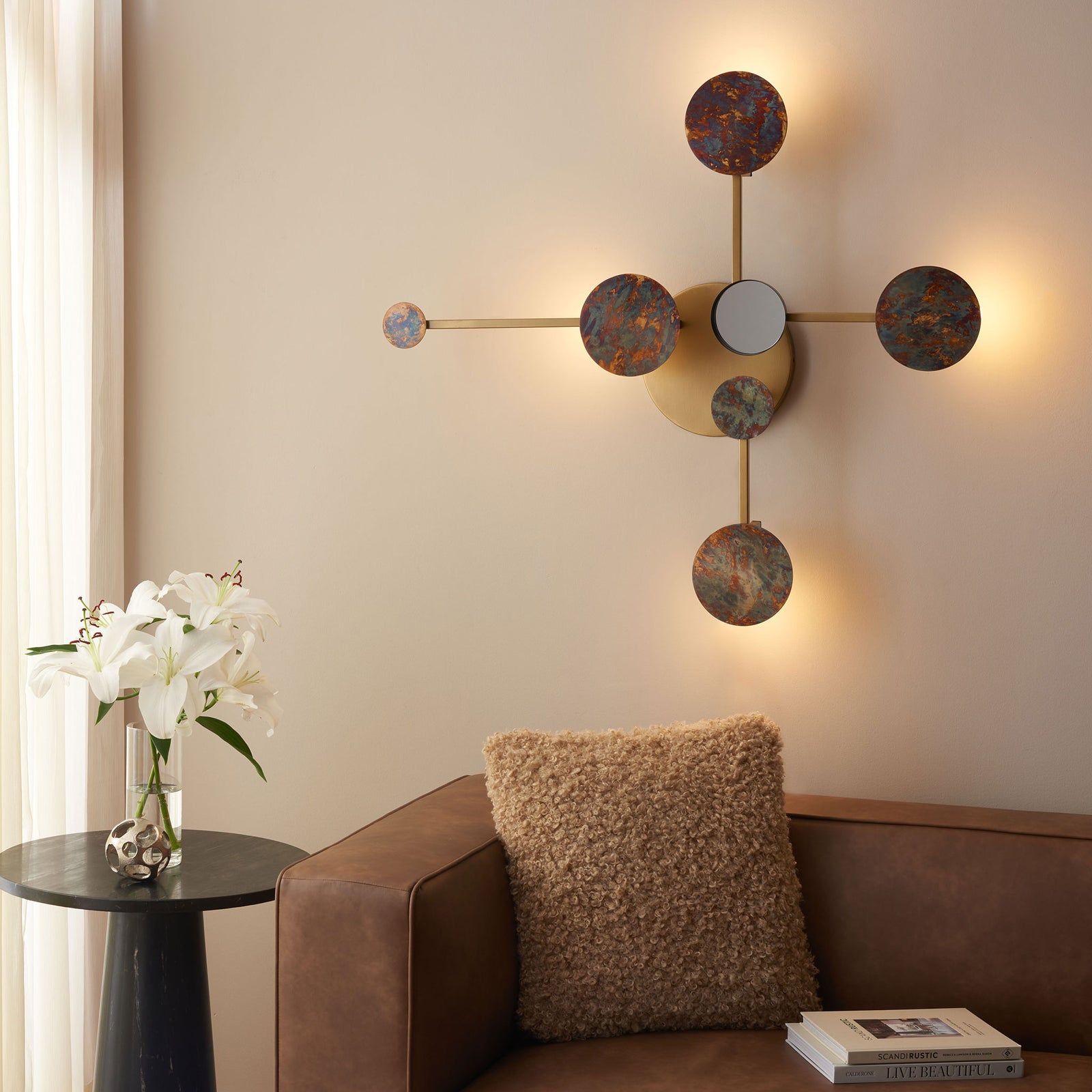 Warm light glows behind textured circular accents, adding ambience to the brass wall decor. || WDC1031A || front_on_room