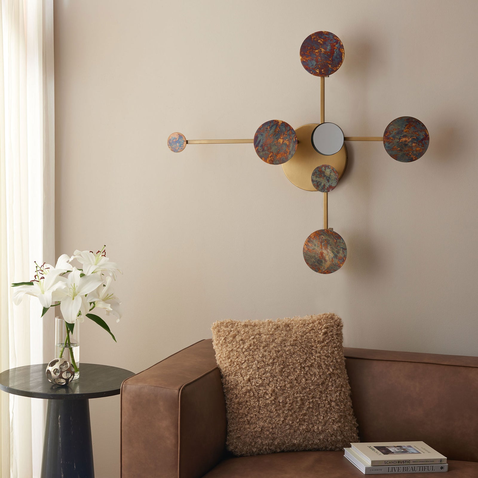 An antique brass wall accent brings mottled circular details and a mirrored center above the sofa. || WDC1031A || front_room