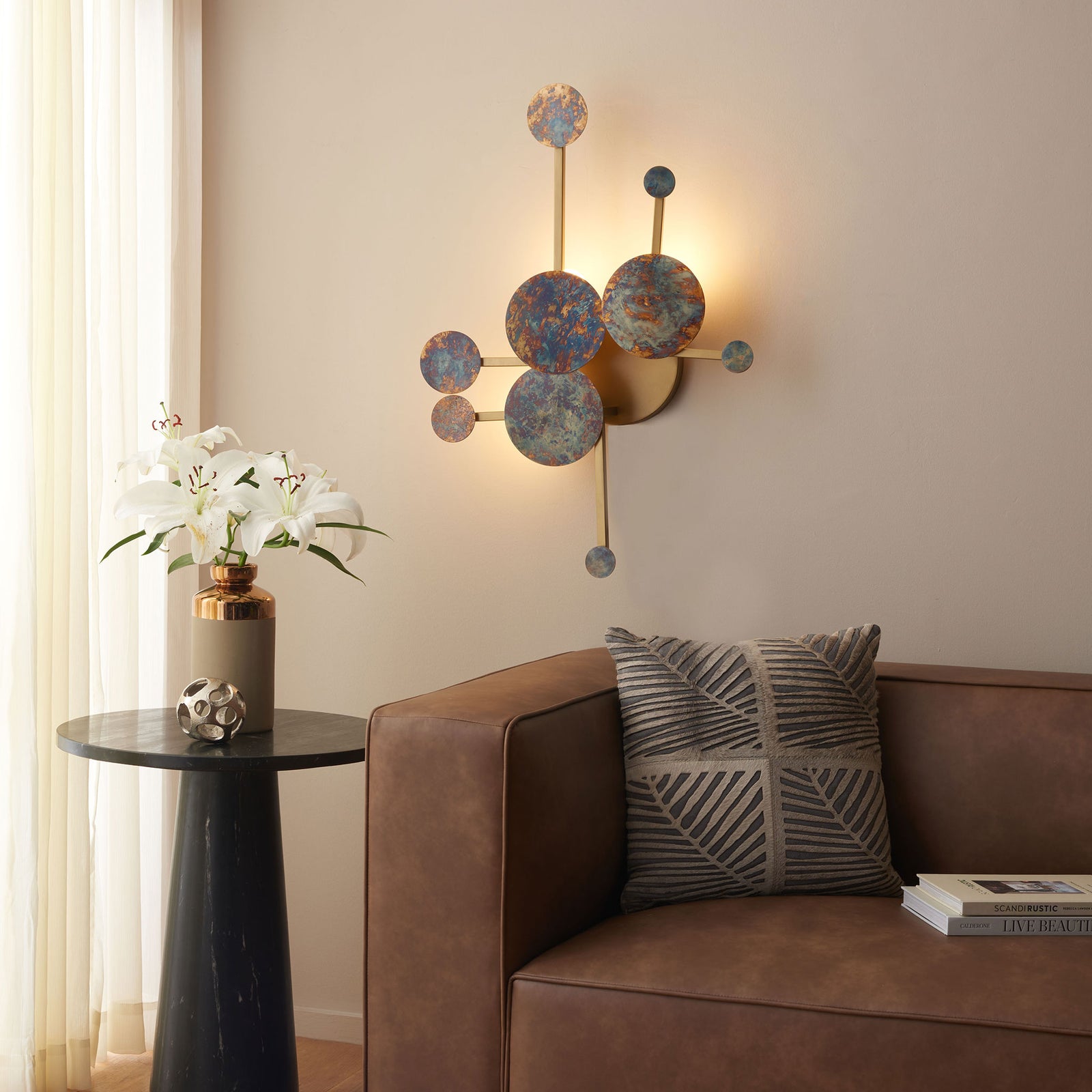 A warm halo glows behind mottled blue and copper-toned circles above a sofa. || WDC1032A || front_on_room