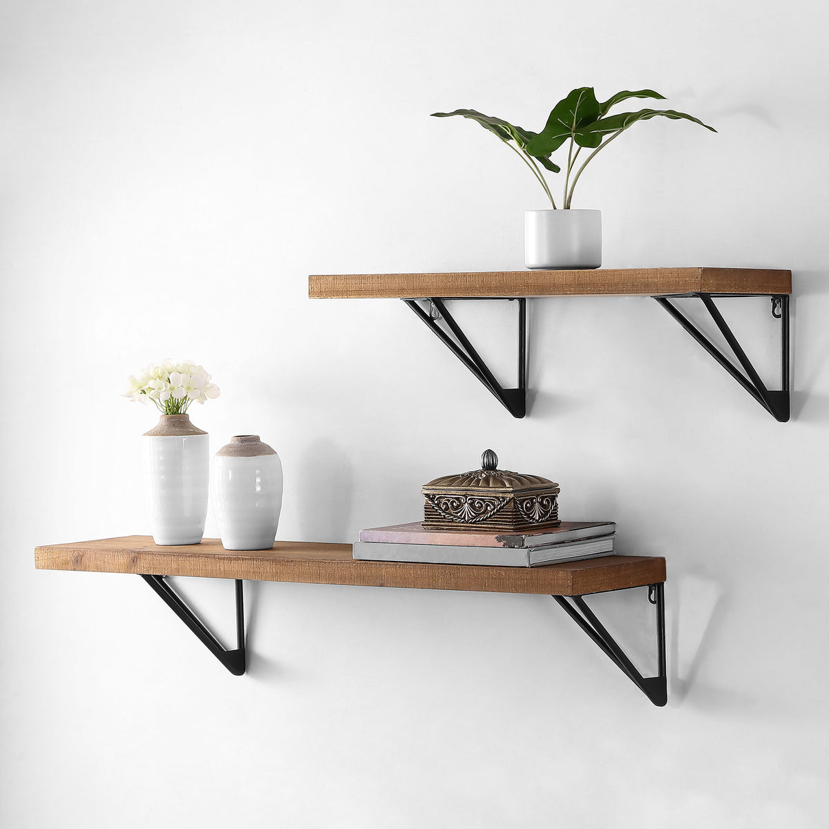 Staggered brown wood wall shelves with black iron brackets hold plants and decorative accents.