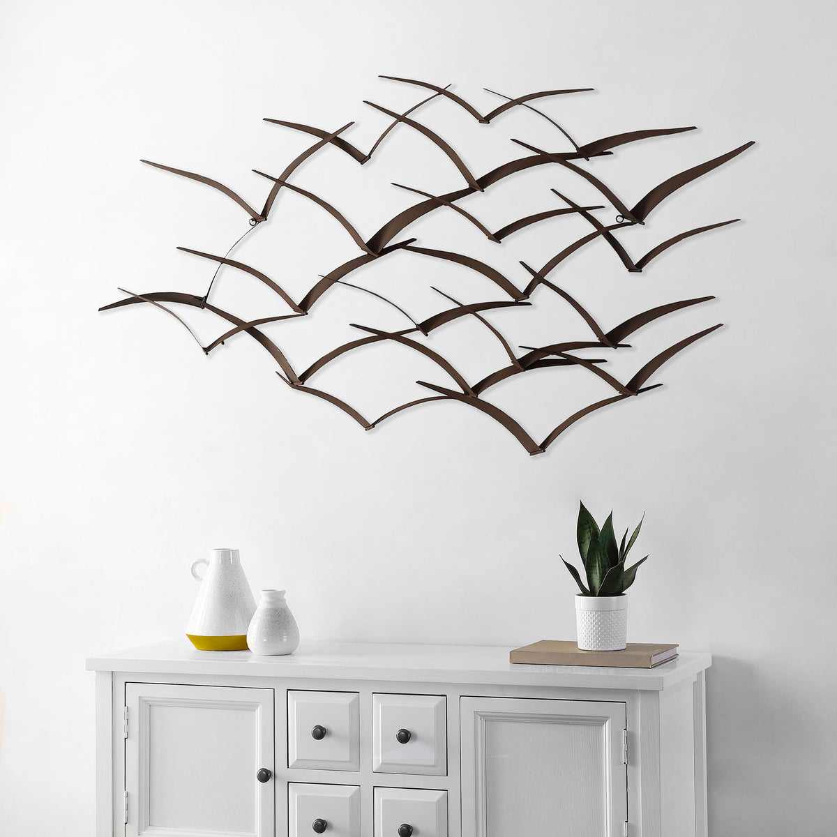 Bronze-finished birds sweep across the wall, creating an airy focal point above a console.