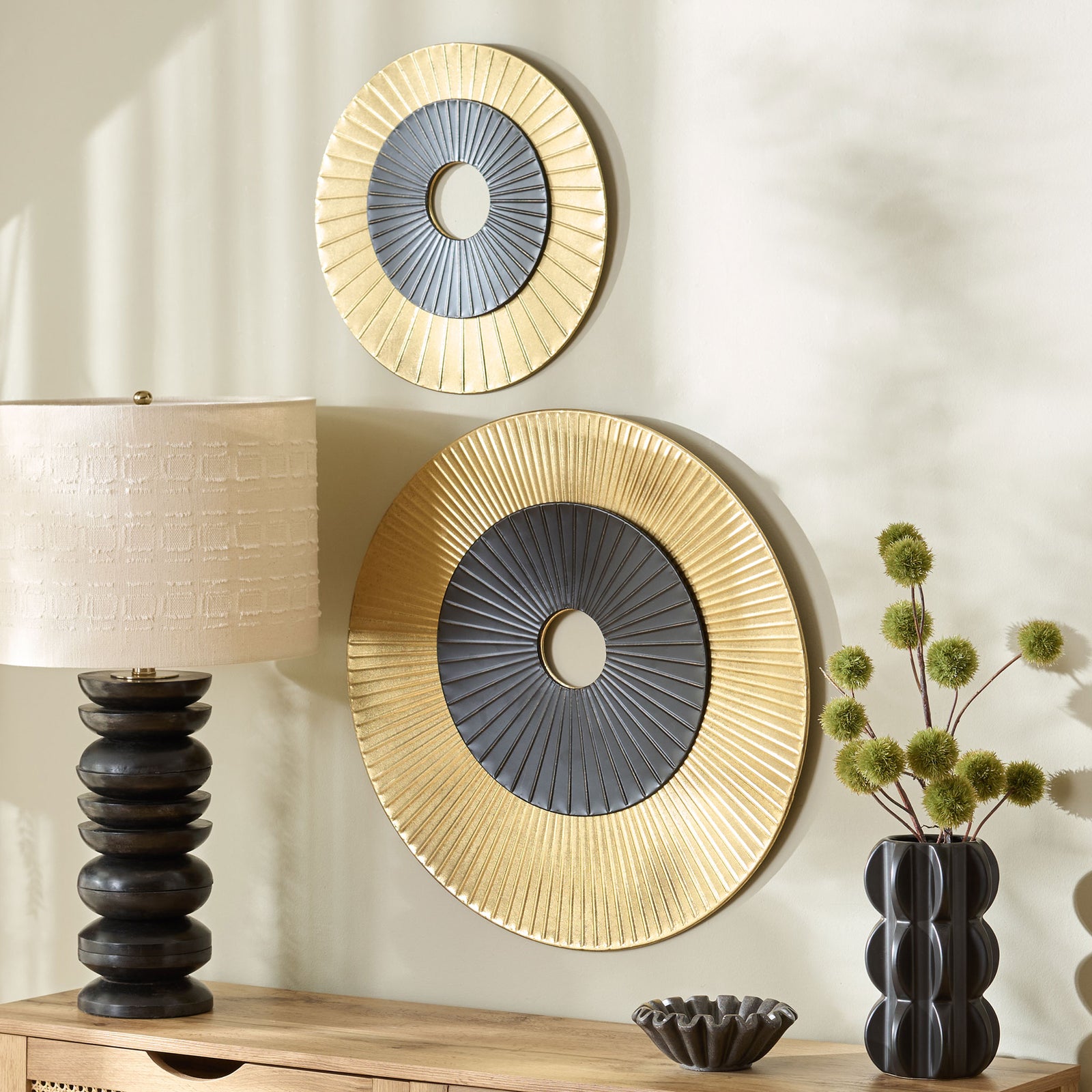 Two gold and black sunburst wall discs add sculptural style above a wooden console || WDC5026A || front_angle_room