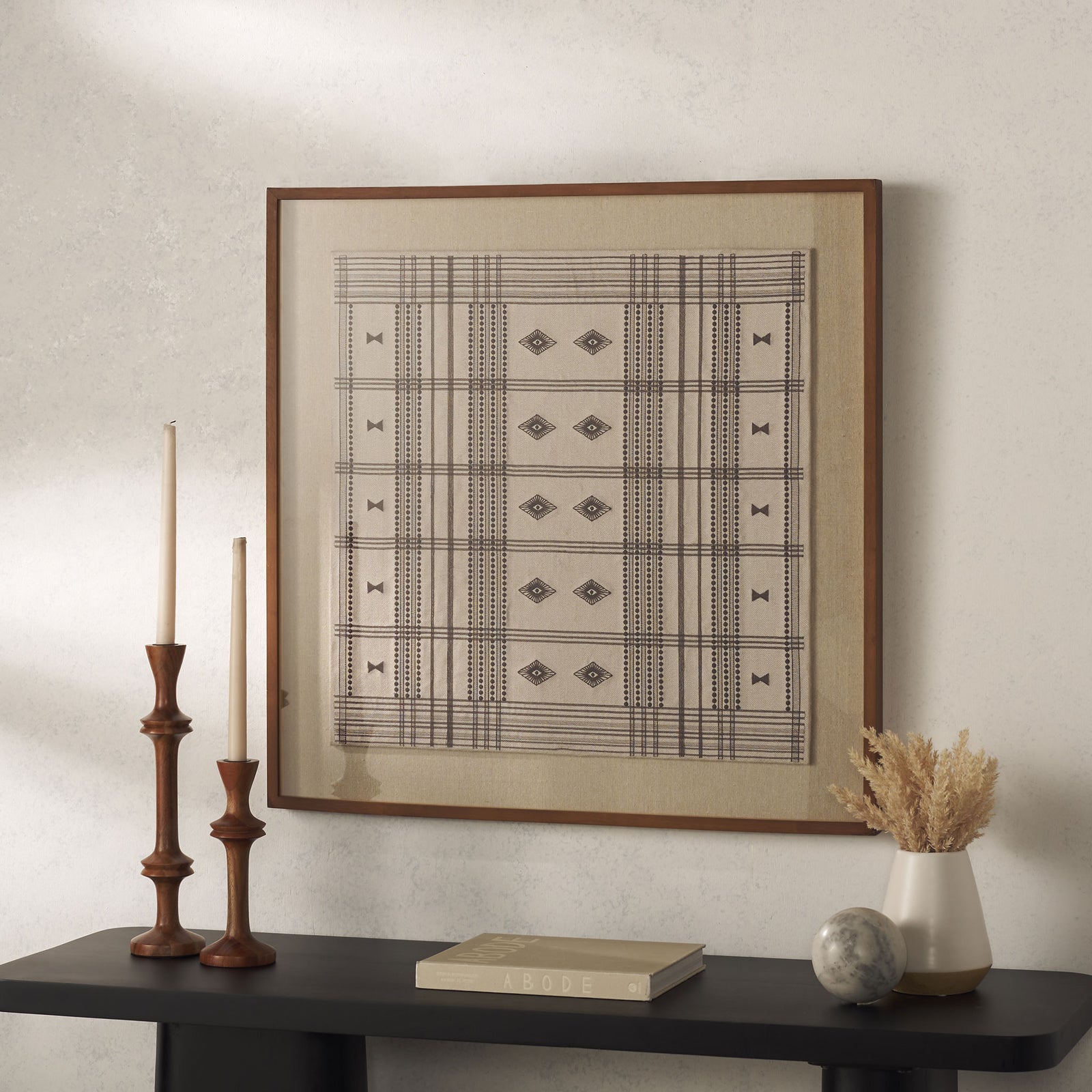 Square wood-framed textile art brings warm cream tones and crisp brown geometry above a console || WLA1904A || front_room