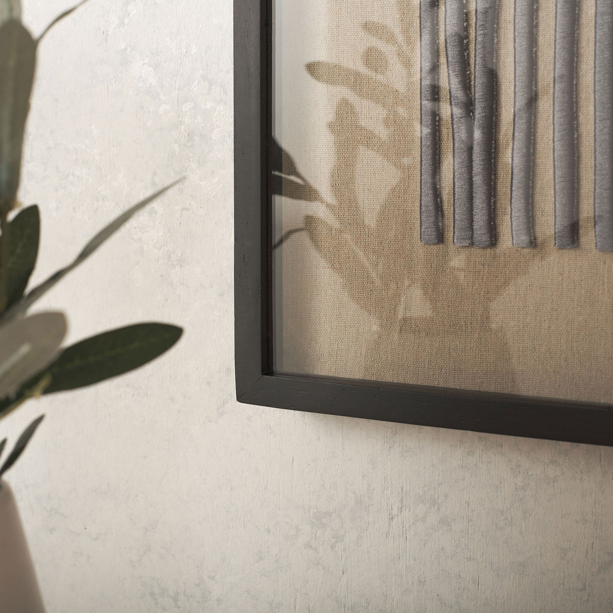 Raised gray-purple embroidery adds texture to natural linen within a slim black frame. || WLA1906A || detail_room