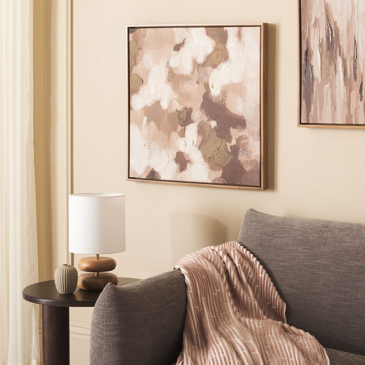 Warm cream and brown abstract art adds inviting texture above a living room sofa.