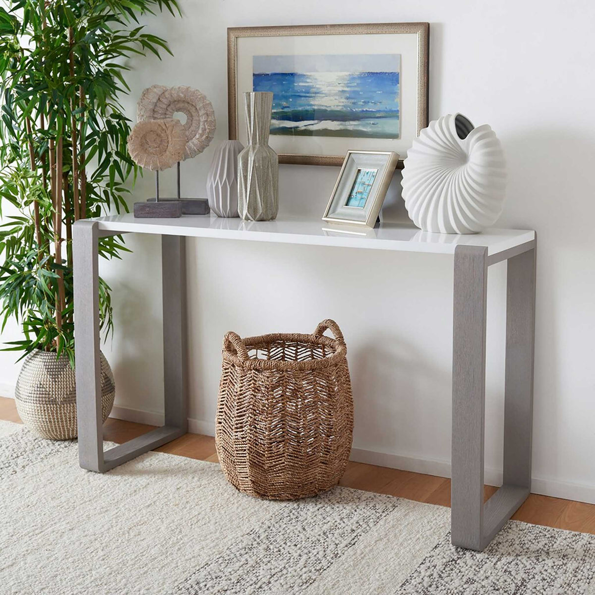 White lacquer console table with gray frame legs displays sculptural accents and framed photos