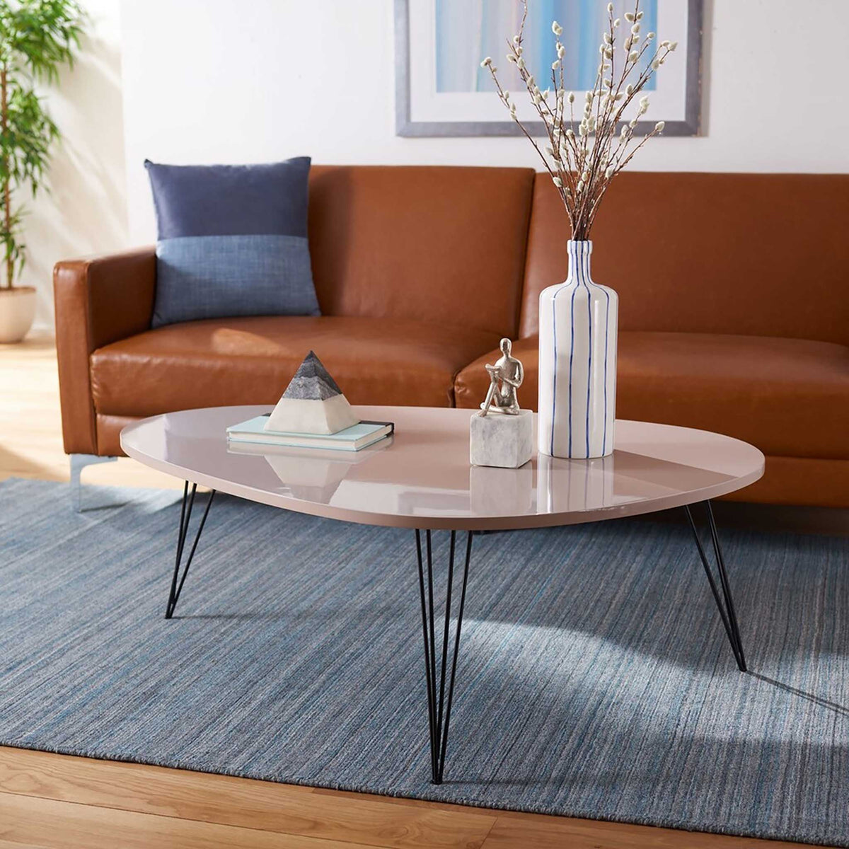 Glossy taupe coffee table with a flowing silhouette and delicate black hairpin legs