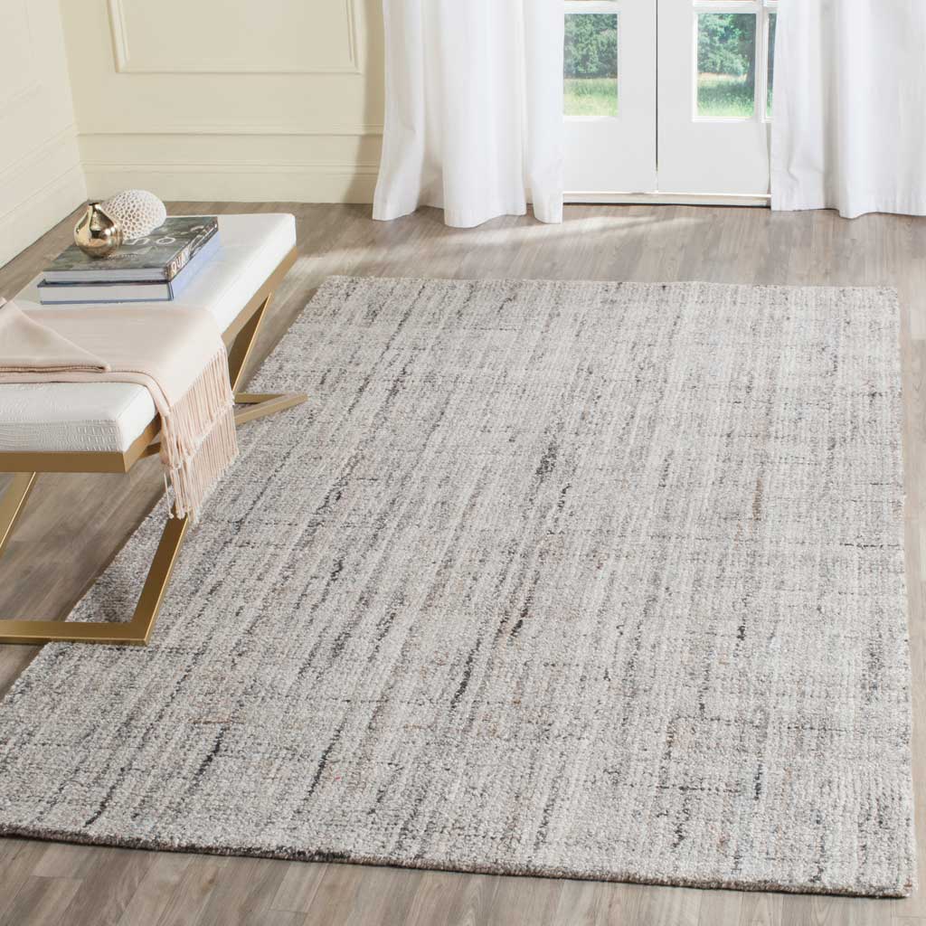 A camel and black rug grounds the space with a muted abstract grid and inviting texture