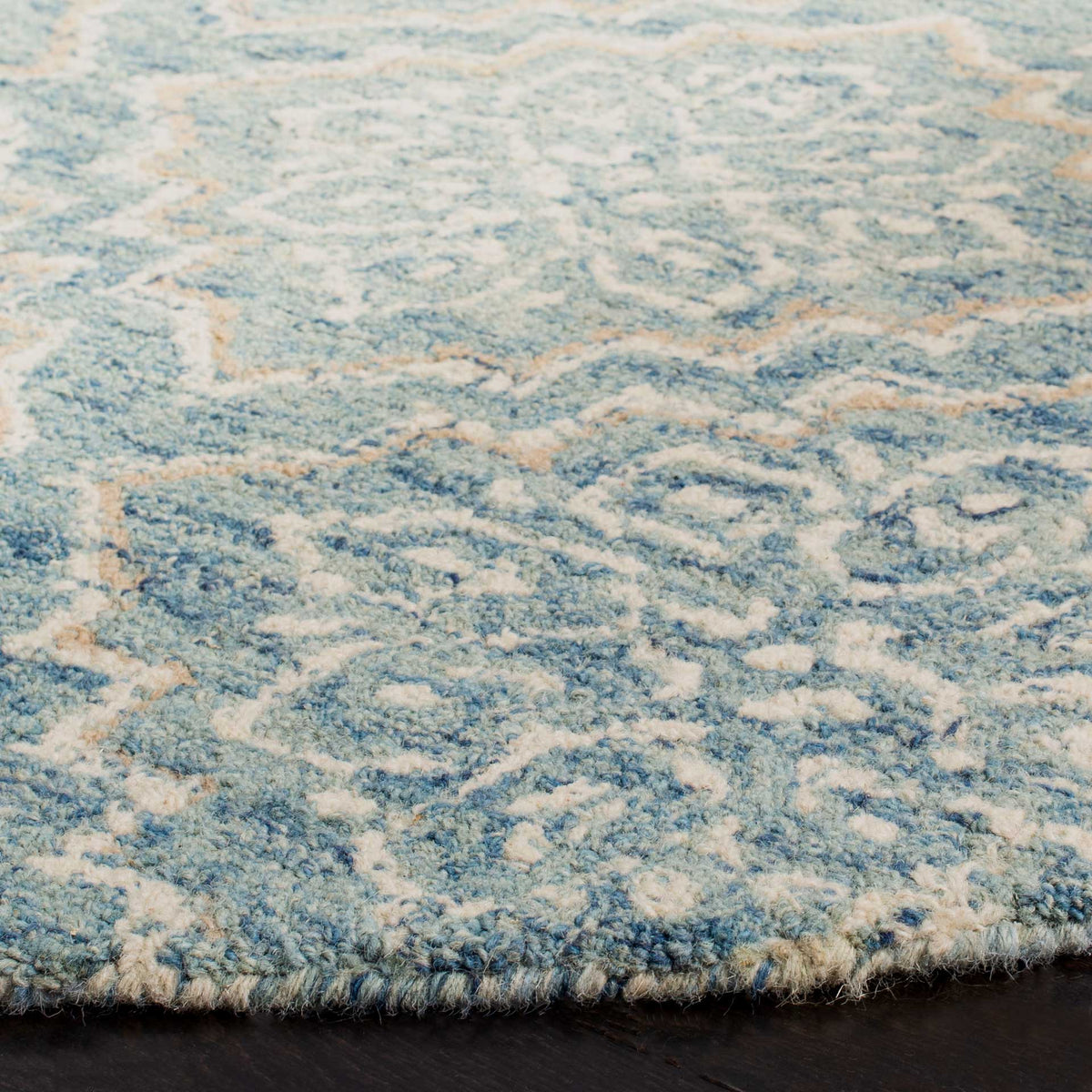 Hand-tufted wool pile adds inviting texture to blue and ivory motifs along the rug's edge.