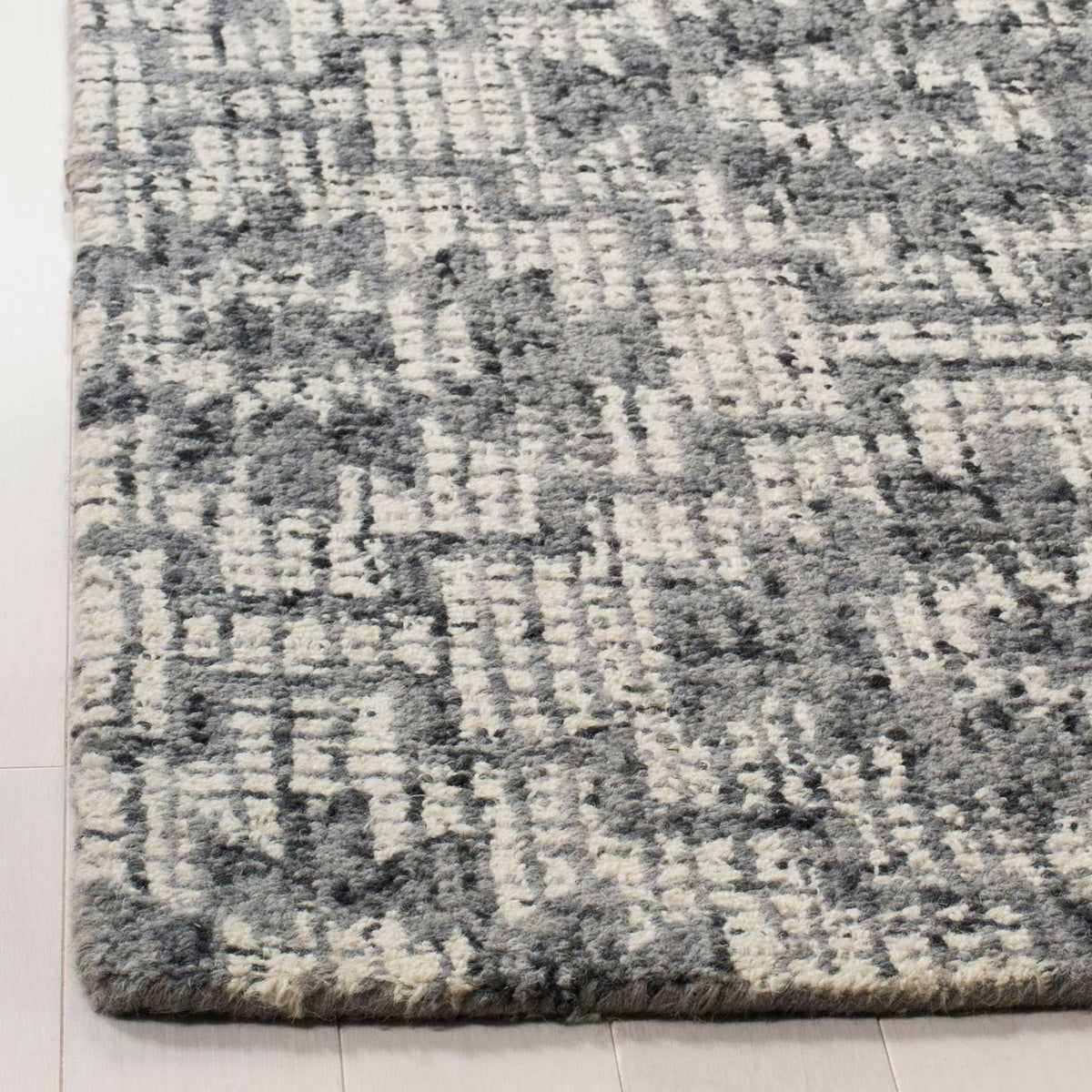 Dense ivory and dark gray wool pile meets a neatly finished rug edge