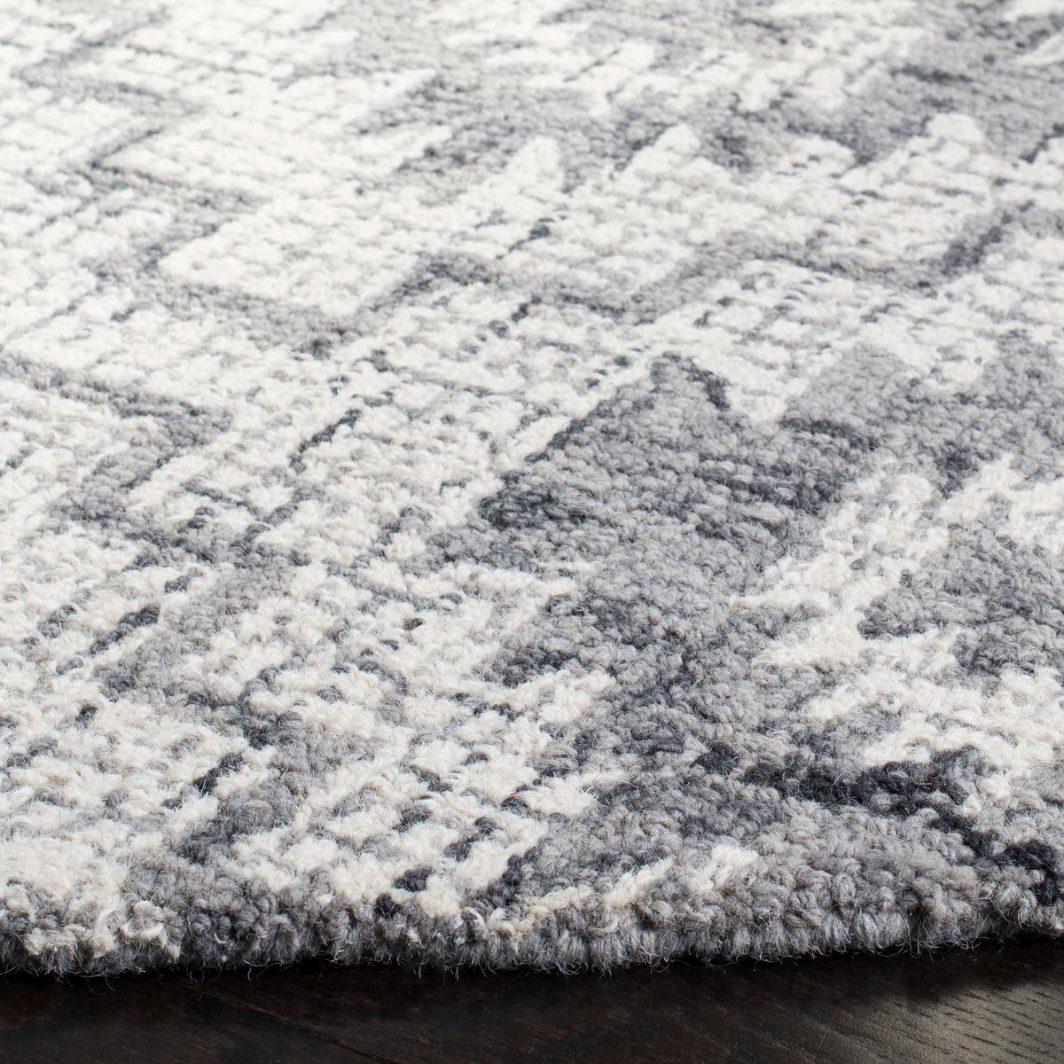 Hand-tufted wool pile blends ivory and dark gray with plush texture and a neatly finished edge