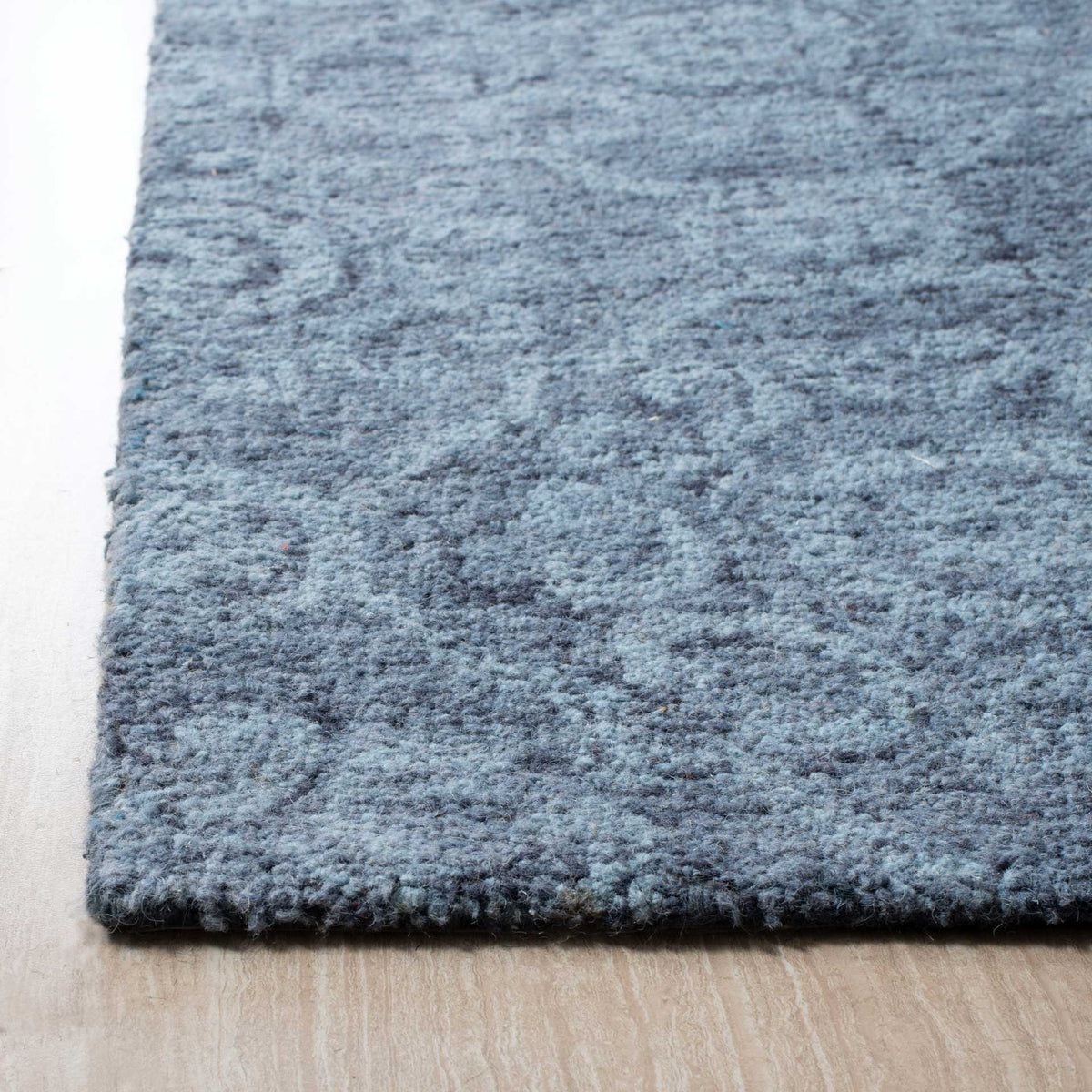 Dense, heathered blue wool pile with a neatly finished edge