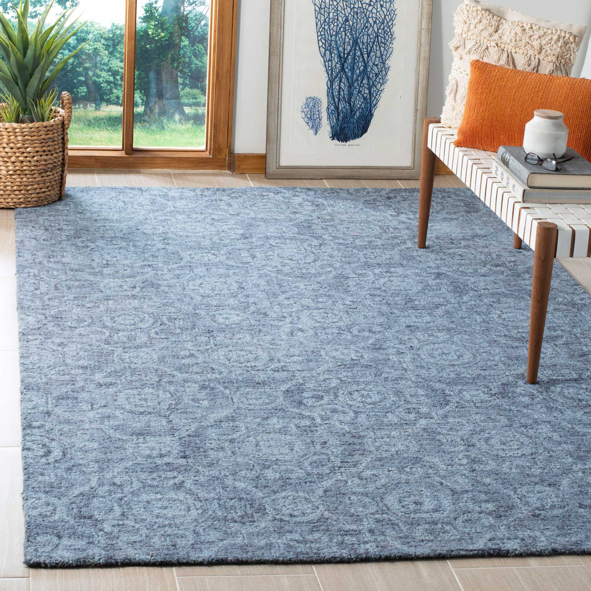Blue wool rug with subtle medallions adds soft texture beside a wood-framed bench