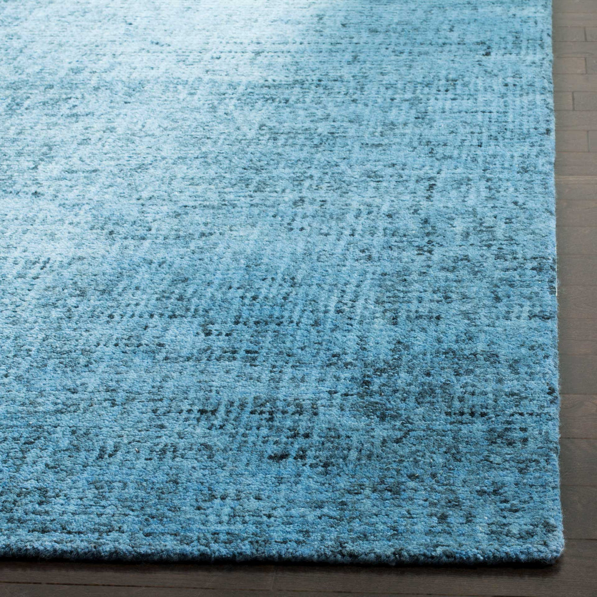 Variegated blue wool pile reveals a softly textured surface and a neatly finished edge.