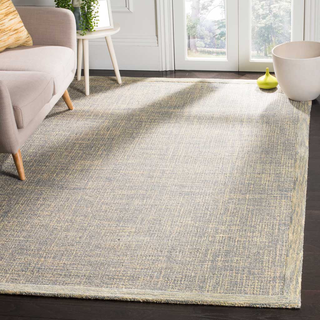 Soft gold accents warm the gray textured rug, finished with a pale contrasting border.