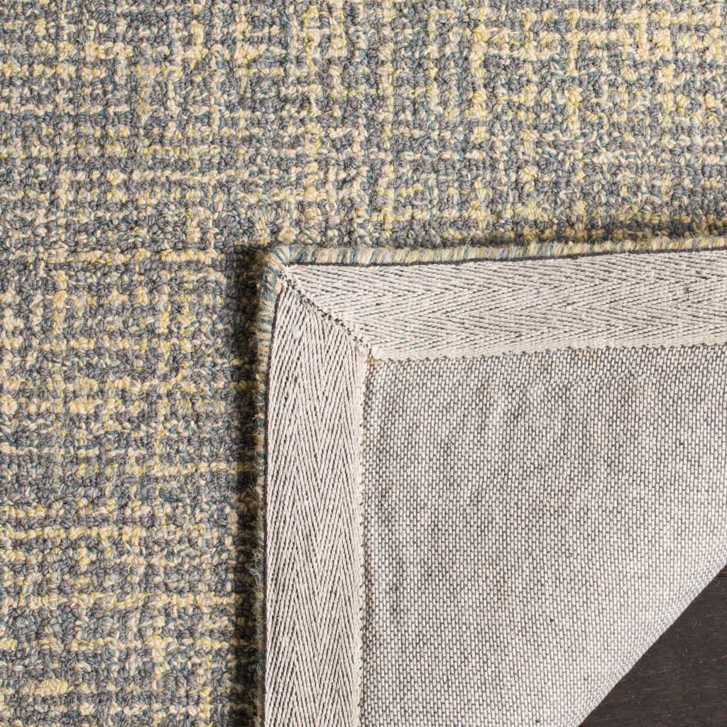 Woven fabric backing and bound edges finish the gold and gray wool rug.