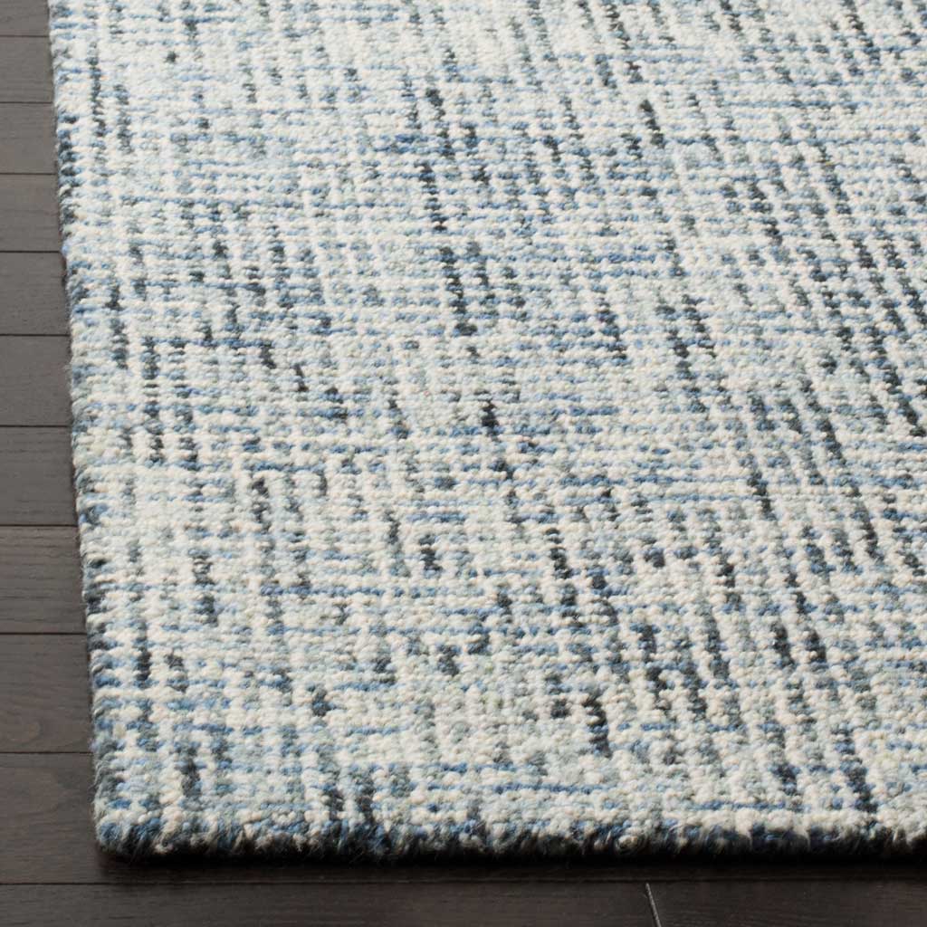 Plush wool fibers and a neatly finished edge enrich the blue-and-charcoal pattern.