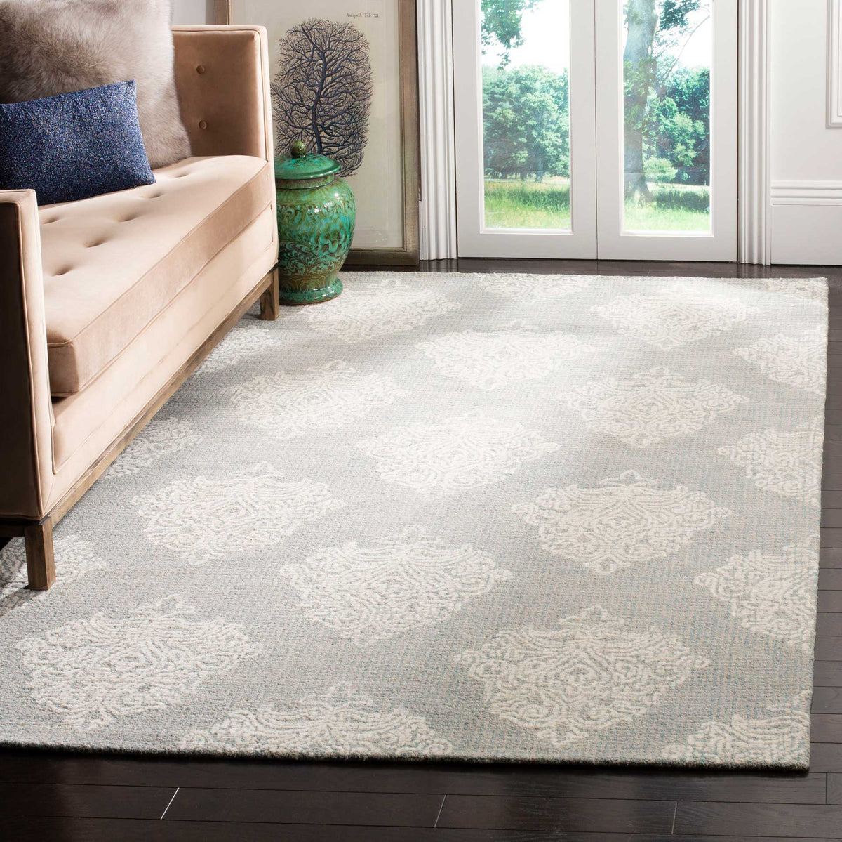 Aqua and ivory damask rug adds subtle pattern and softness beside a neutral sofa.