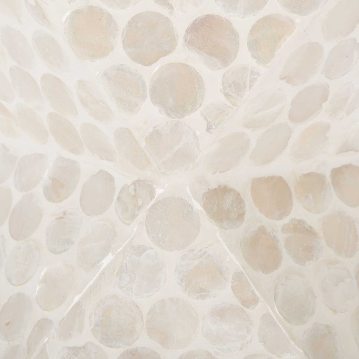Crisp diagonal seams accent the table's faceted form beneath a capiz shell mosaic.