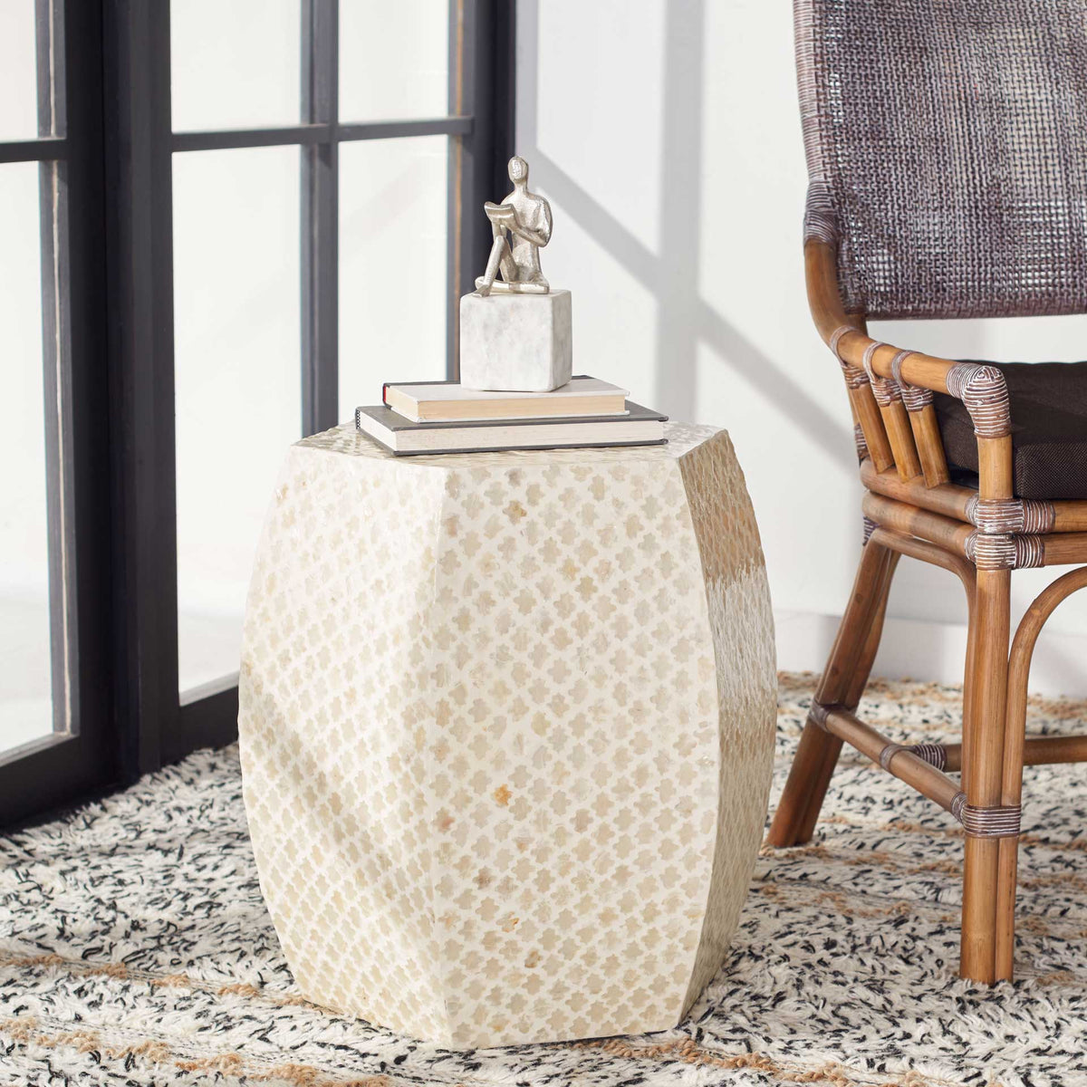 A softly curved, capiz-inlaid accent table offers space for books and decor beside a chair