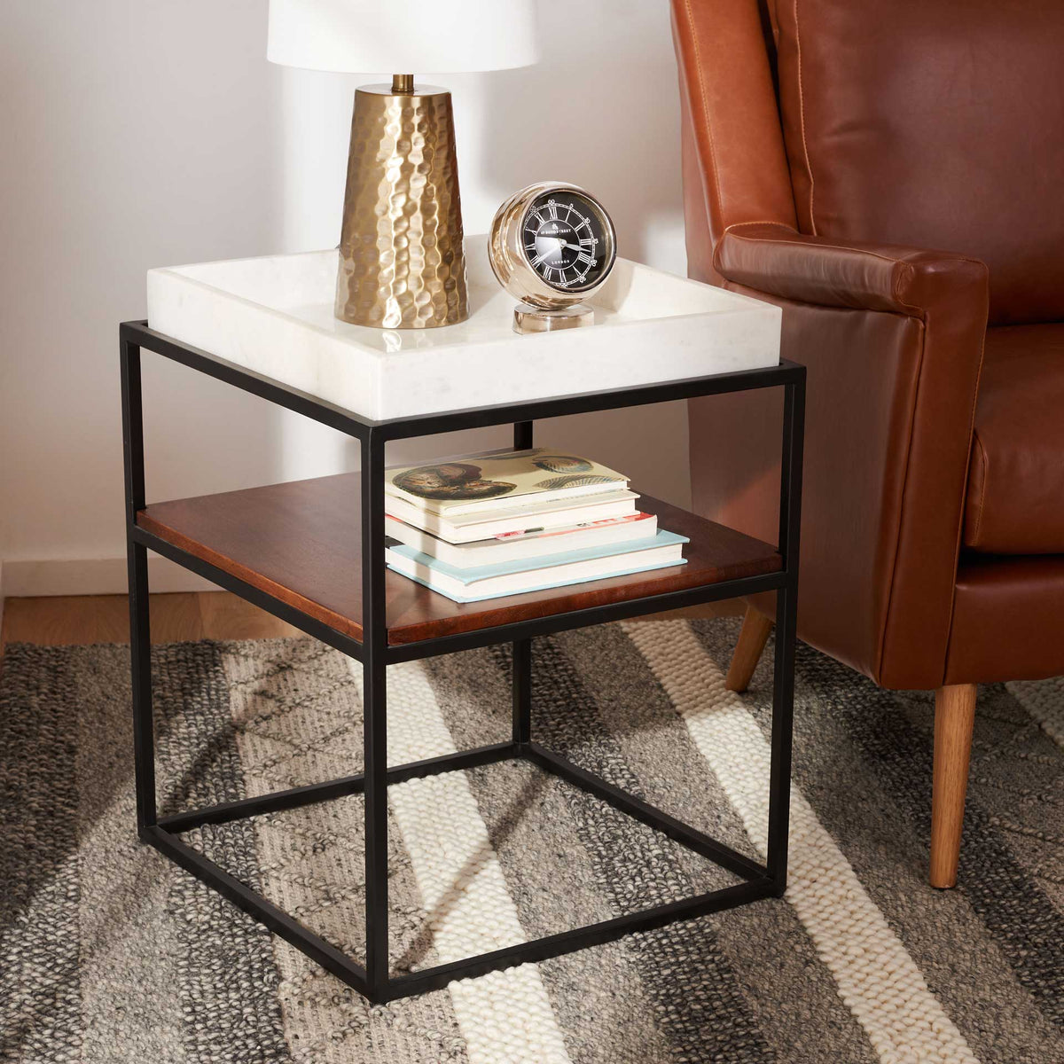 A marble tray keeps decor at hand, while the walnut shelf holds books beside a cozy chair.