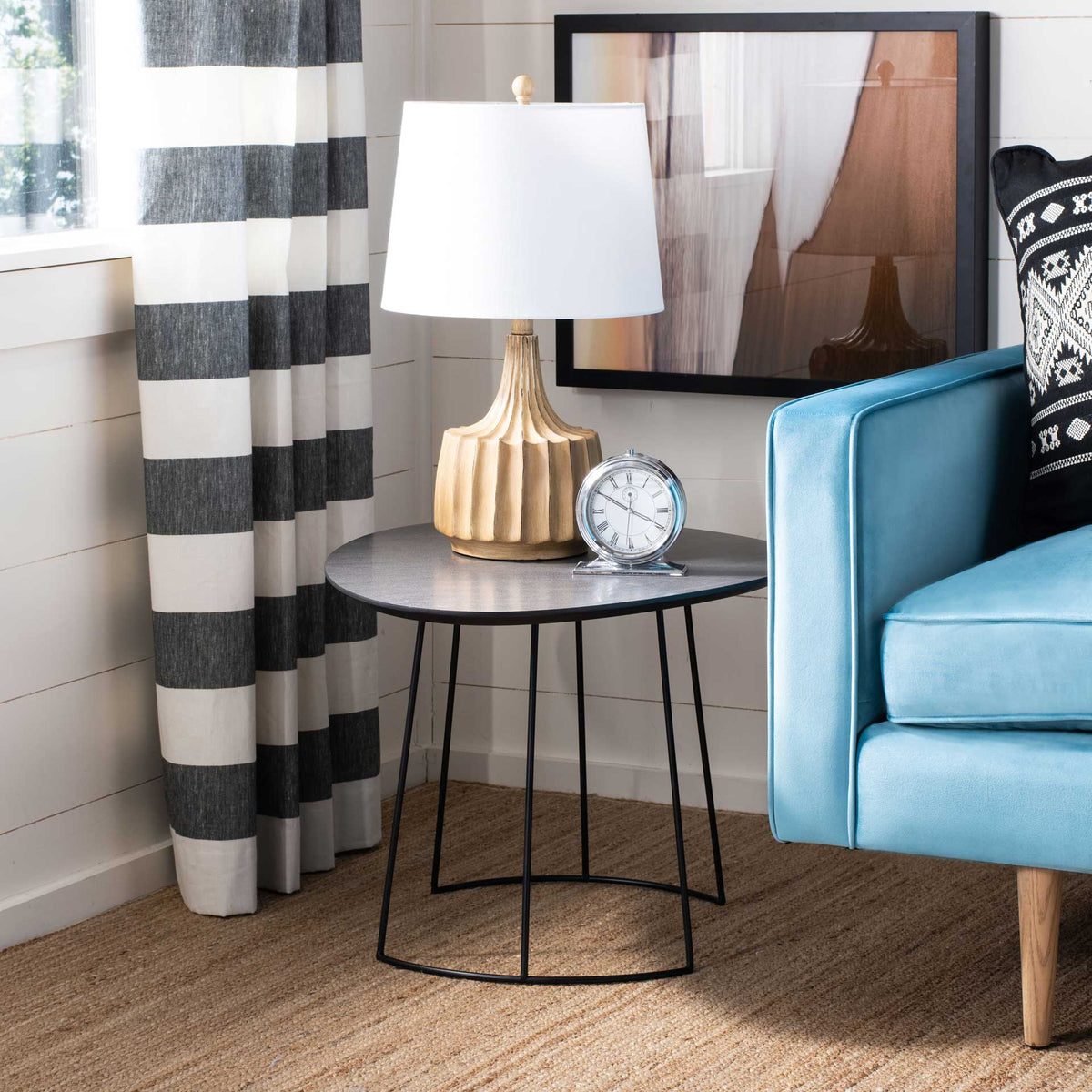 A dark gray side table holds a lamp and clock above an open black iron base.