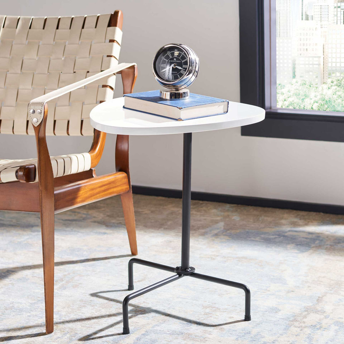 Bright white top displays decor above an airy tripod of black metal legs.