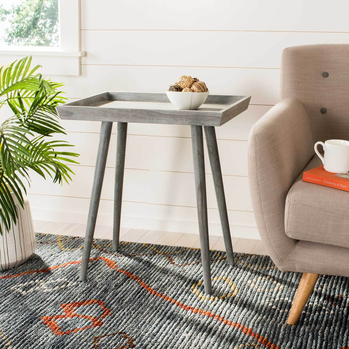 A slate gray tray table adds handy display space for decor beside a plush armchair.