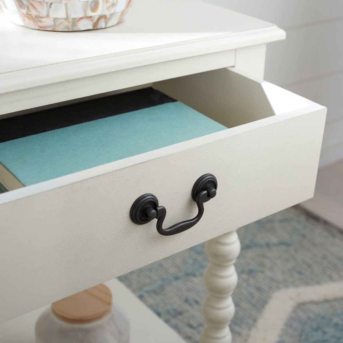 An open white drawer keeps books and small essentials neatly tucked beneath the tabletop