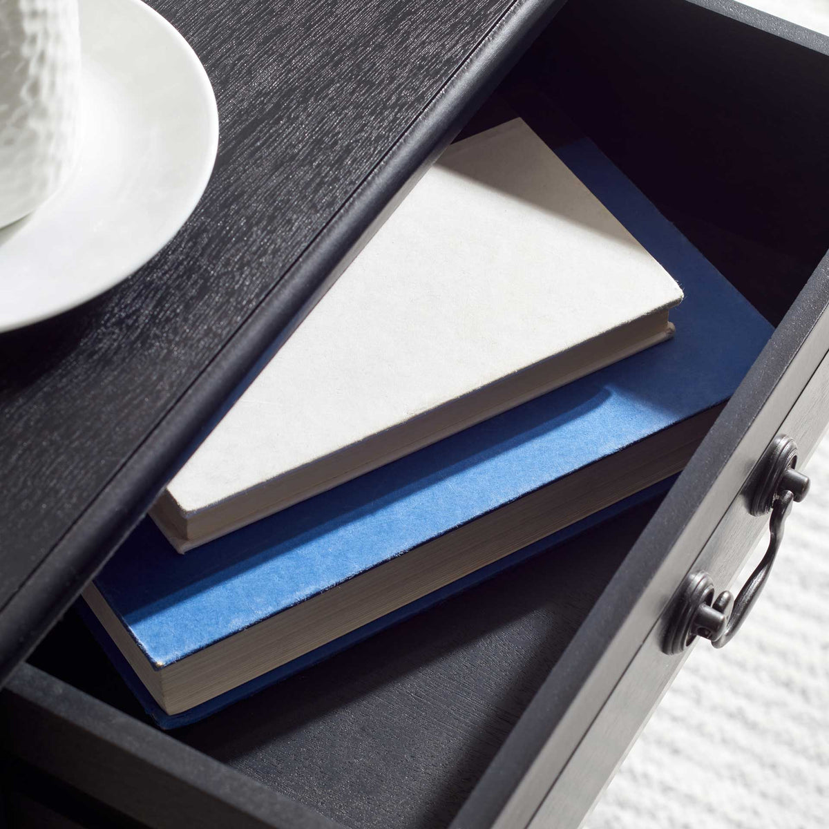 Deep black drawer holds books and notebooks beneath a wood-grain tabletop