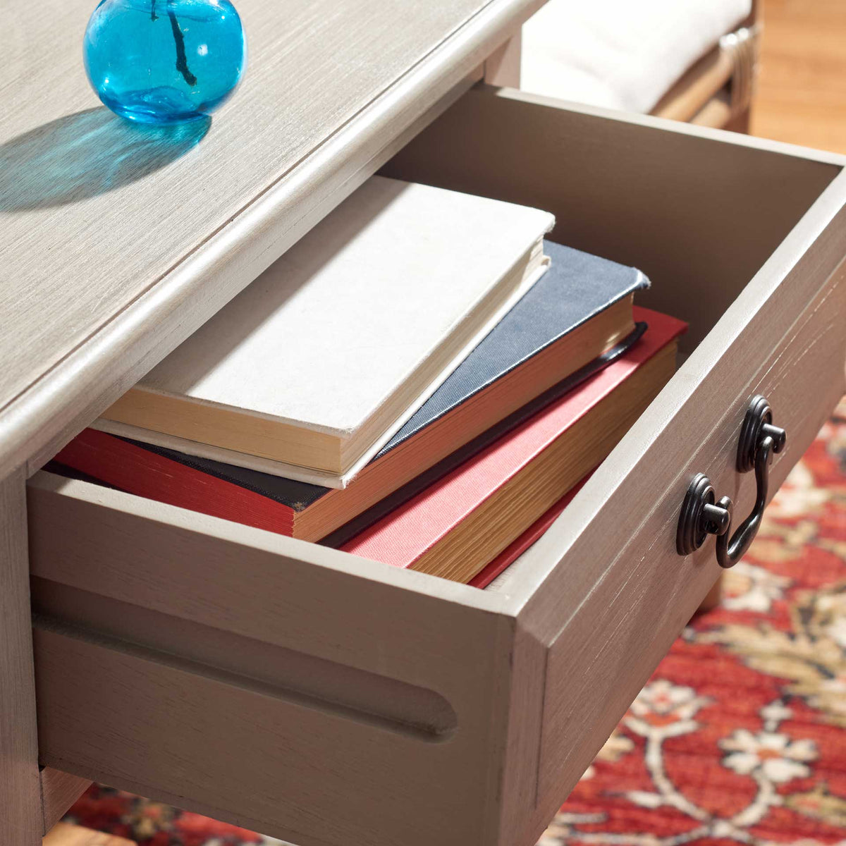 Open greige drawer accommodates stacked books and small essentials under the tabletop