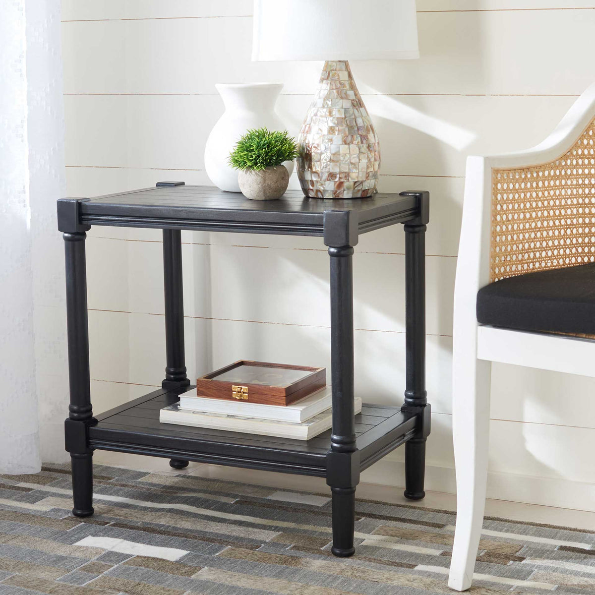 Black accent table with a lower shelf for books and a top for a lamp and greenery