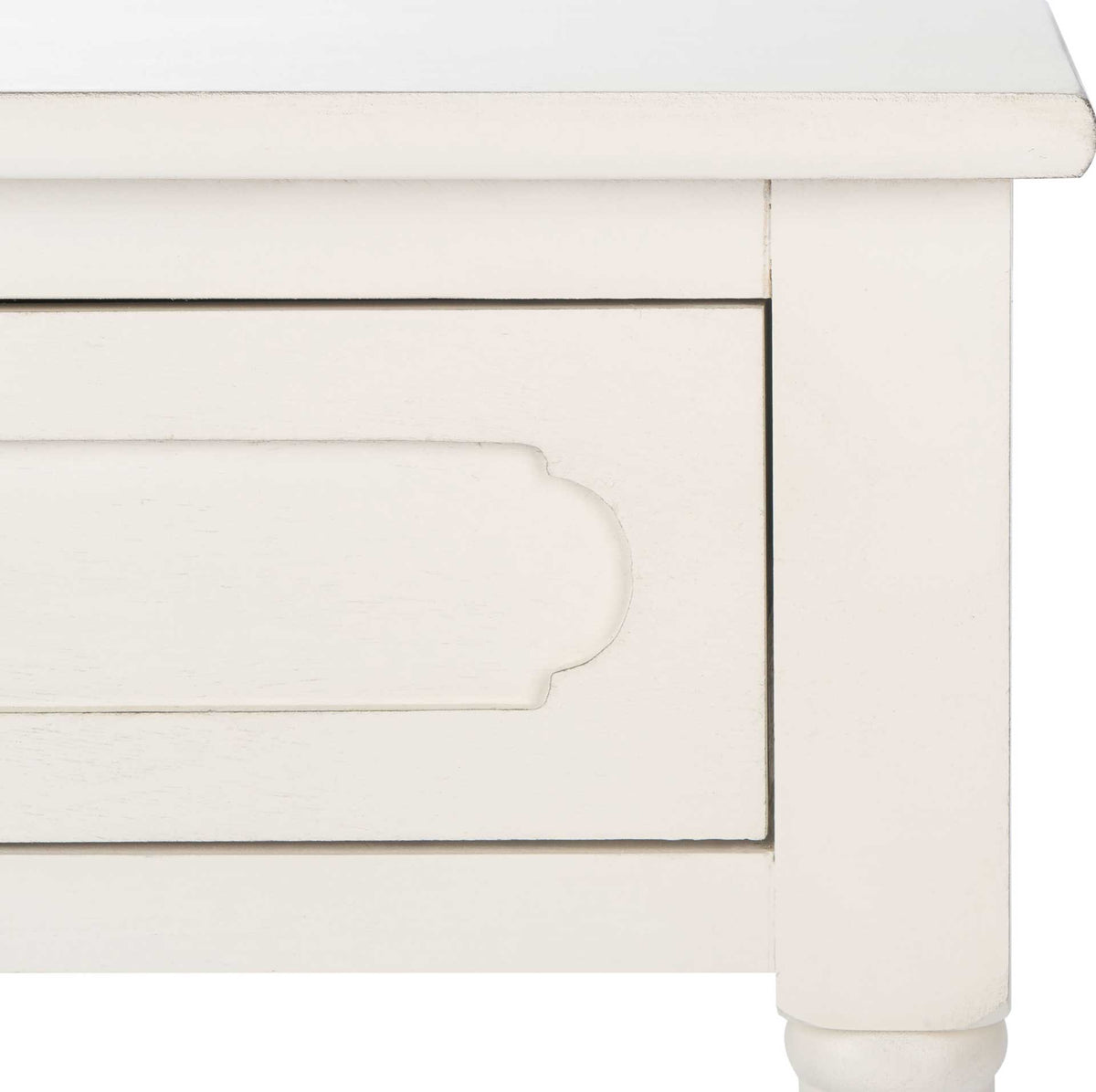 Subtle distressing outlines the white table's carved drawer panel and softly beveled tabletop edge.