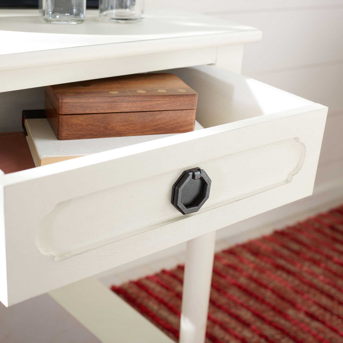 The open white drawer holds a wooden box behind a carved front with a dark metal pull.