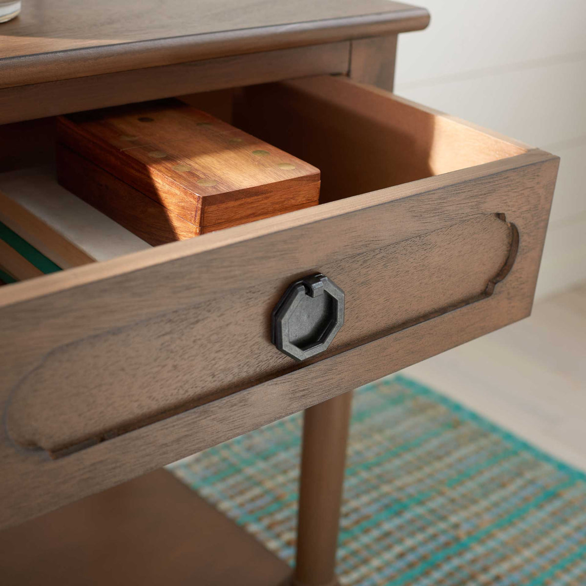 The open brown drawer holds small keepsakes behind a carved front with a dark metal pull.