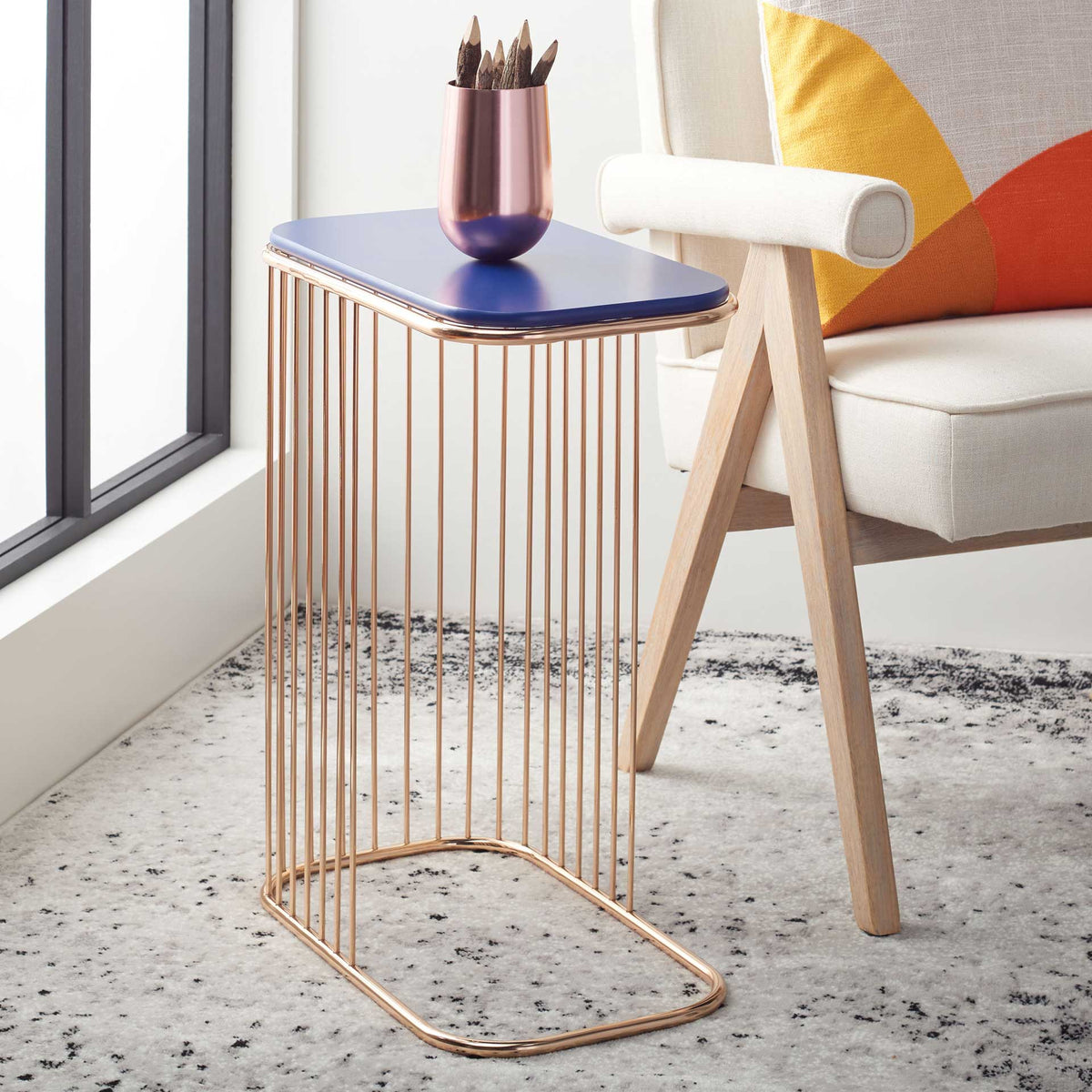 A blue tabletop and gleaming gold frame bring a colorful accent beside an upholstered chair