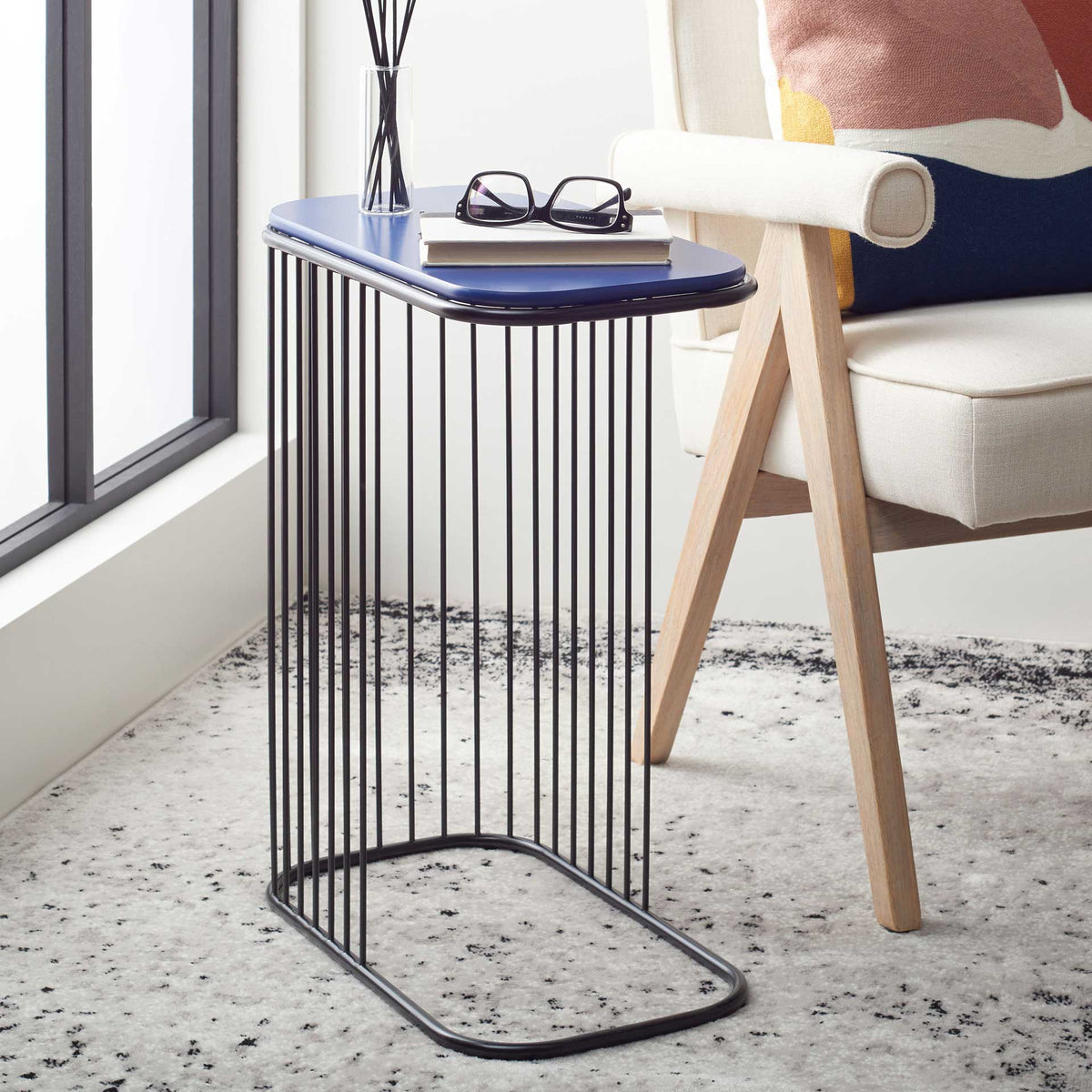 A blue-topped table with an airy black frame tucks neatly beside an upholstered chair