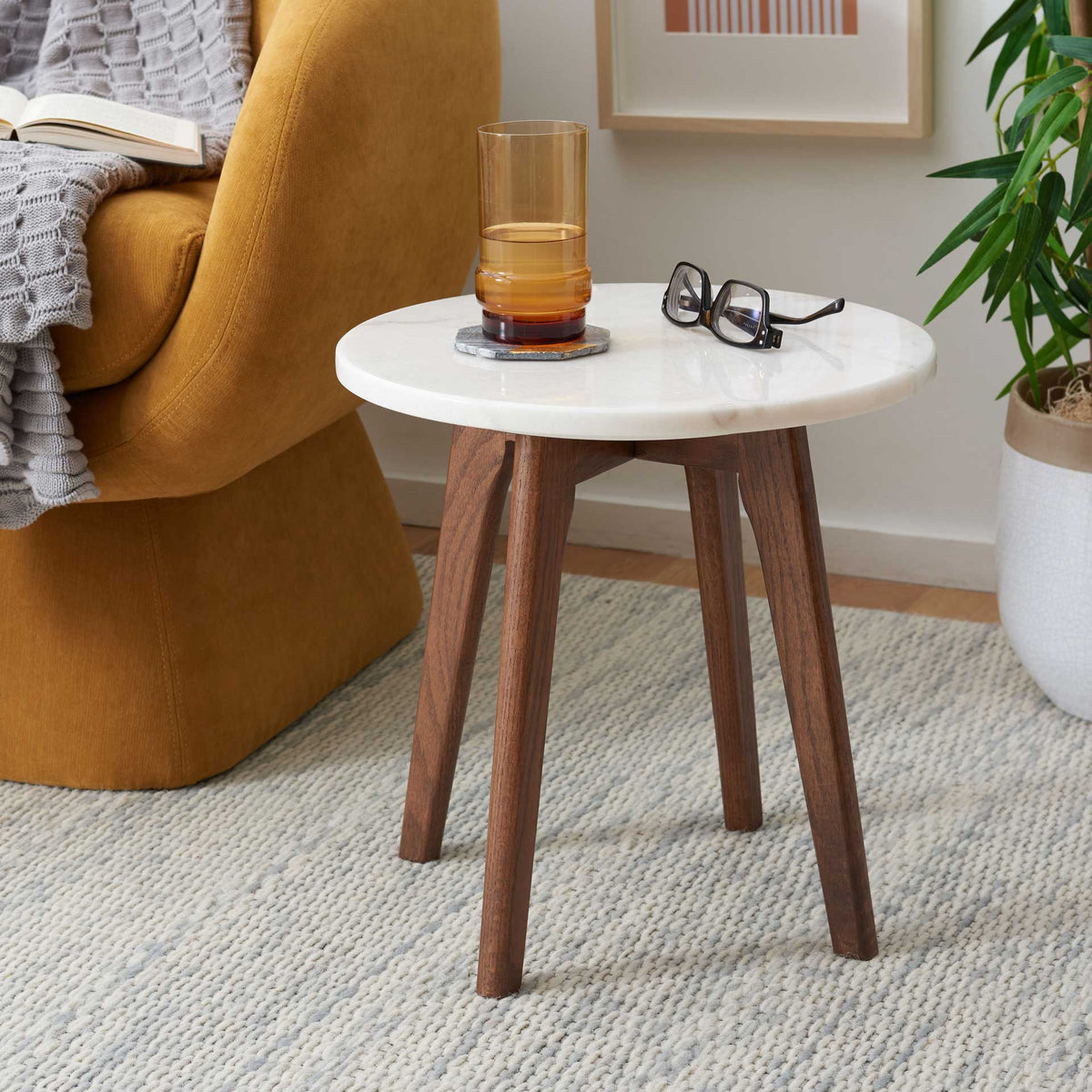 The compact marble top keeps drinks and essentials handy beside a cozy chair.