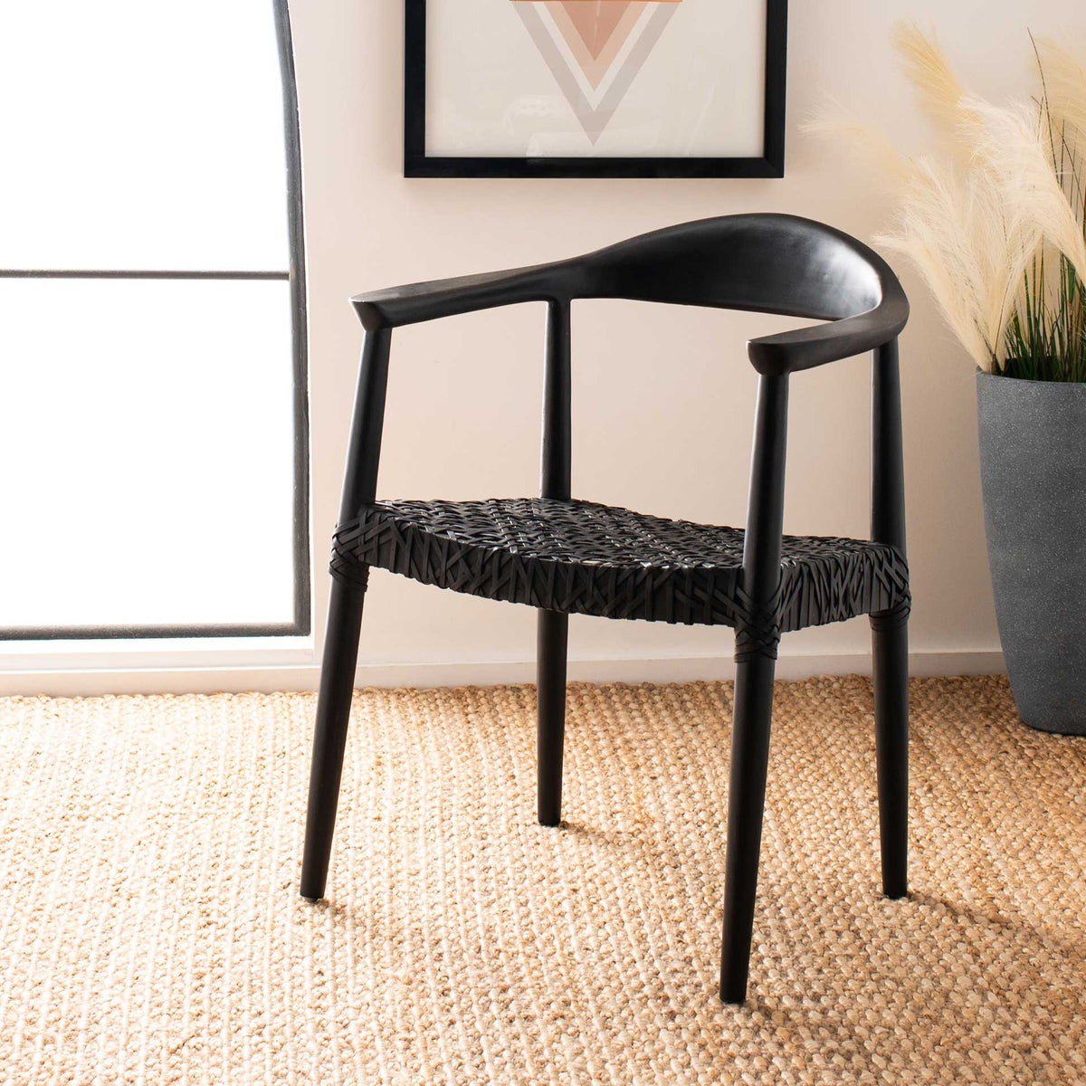 A sculpted black wood frame and textured leather seat add striking contrast to a bright room.
