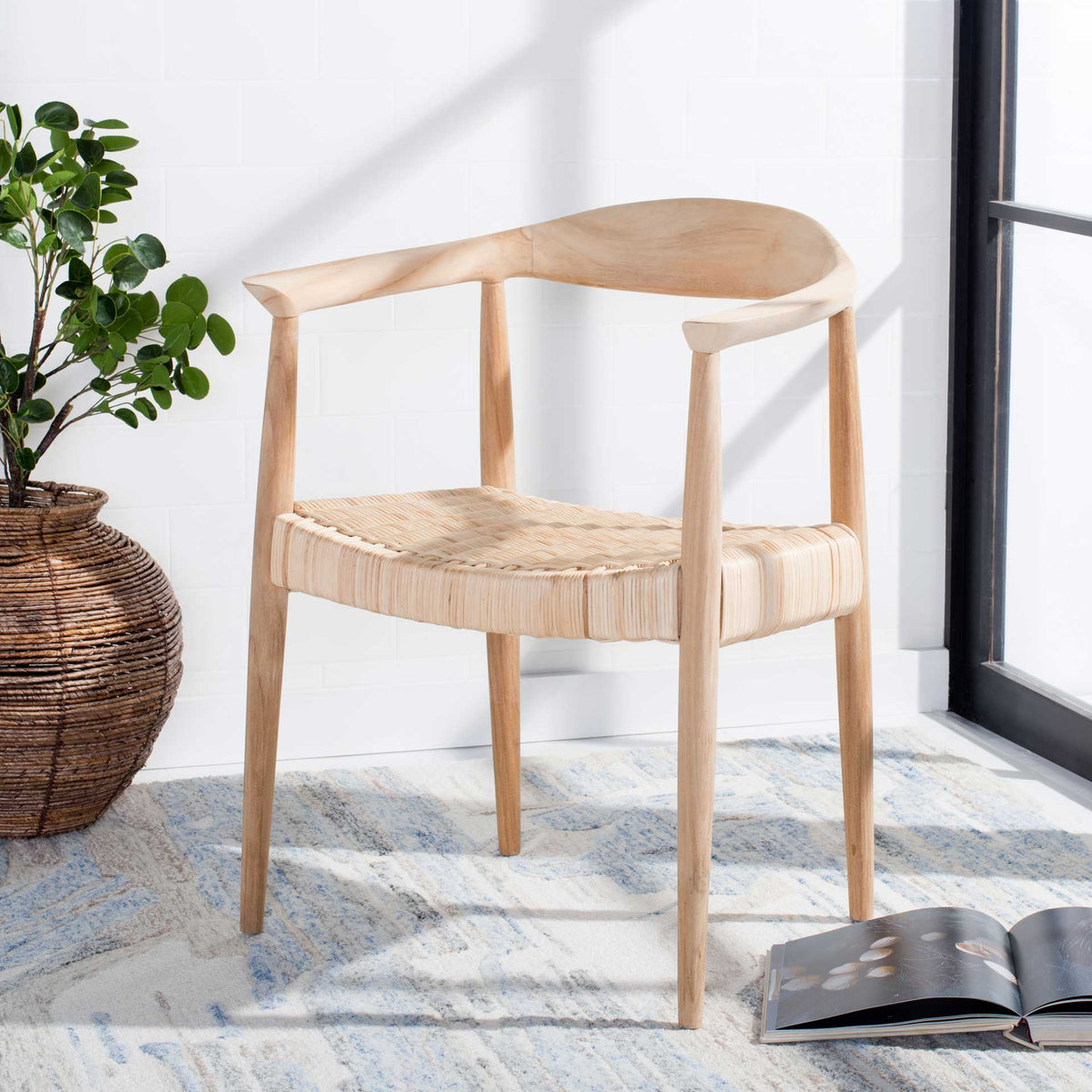 The curved teak backrest and woven rattan seat add warmth and texture to a bright living space.
