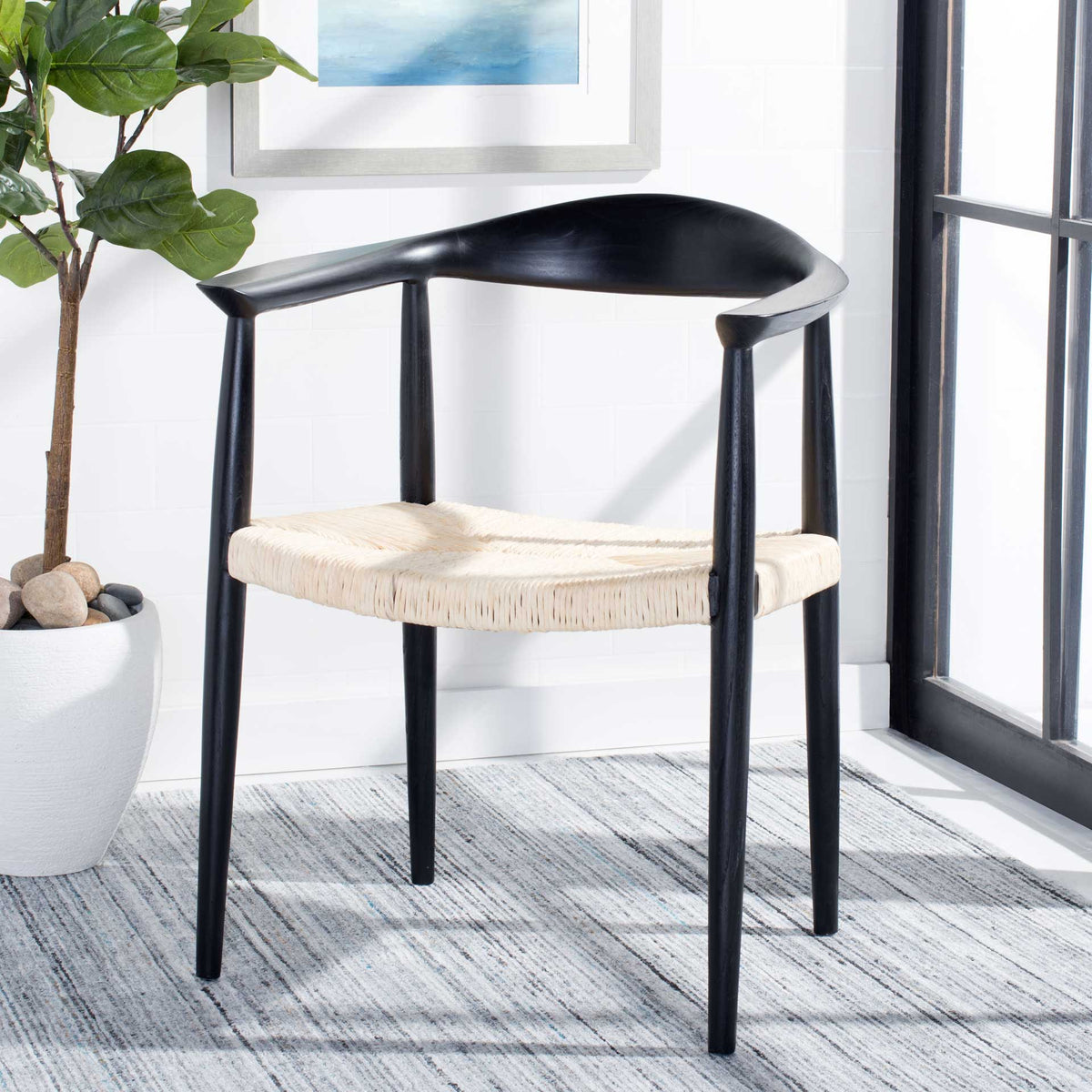 Black wood and pale woven rattan lend sculptural contrast and a modern-coastal feel.