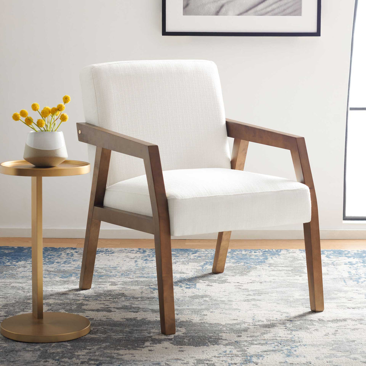 Soft white cushions and angular brown wood arms bring an airy, welcoming feel to the room